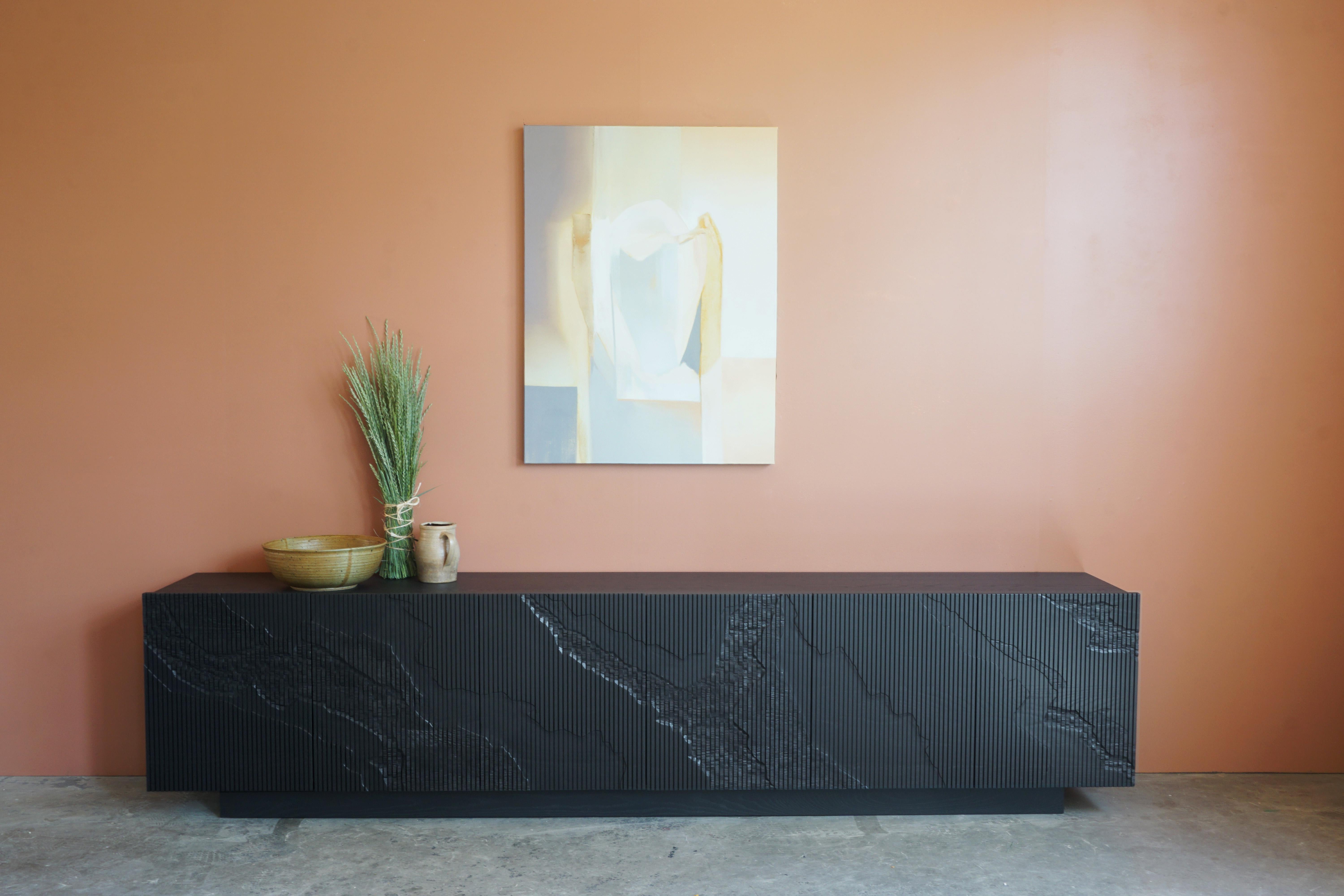 Both monumental and subtle, the Shale Credenza brings the intricacies of nature’s geology indoors. The wood doors are scored vertically across the grain, and details of a cliff’s facade, mapped out by Simon Johns, are carved into them replicating