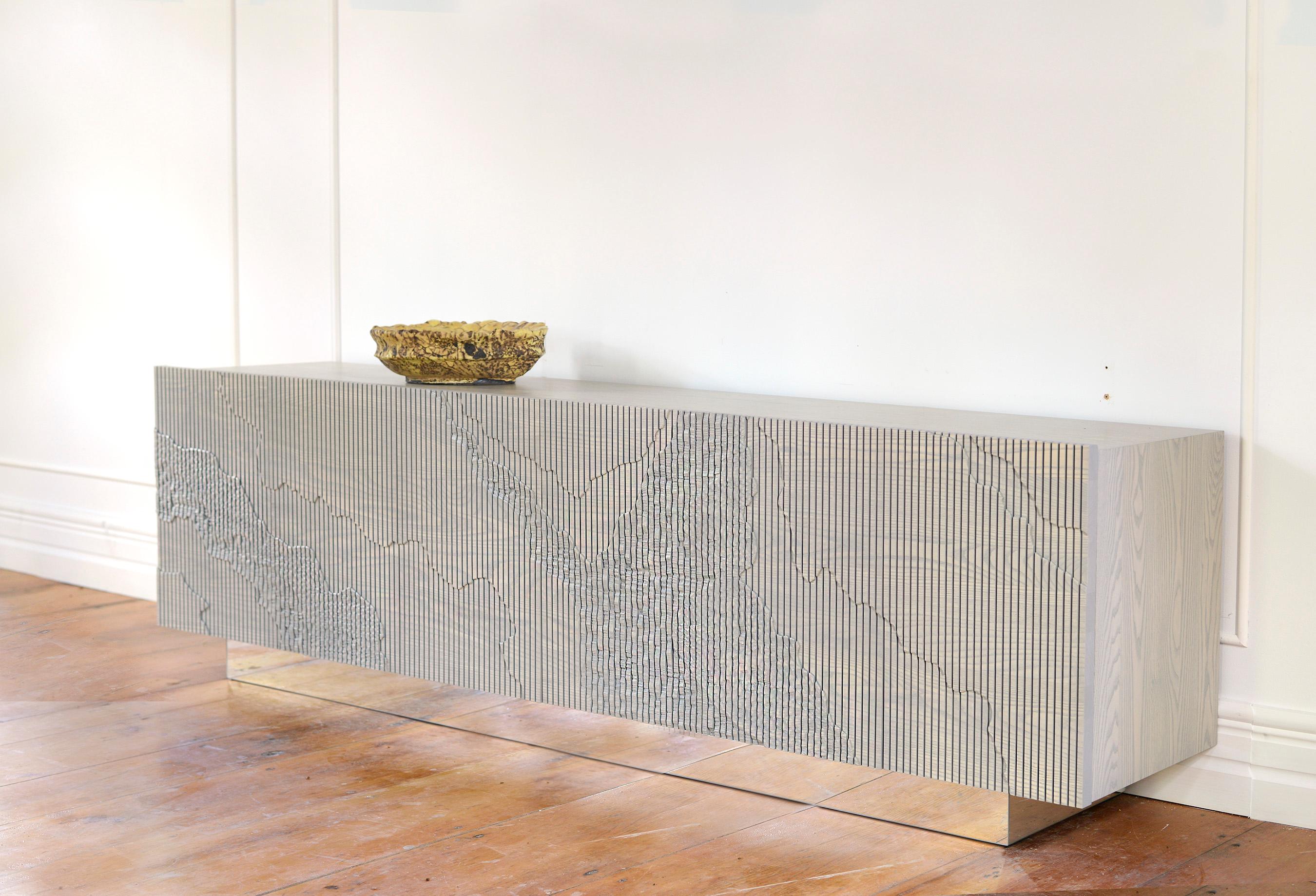 Both monumental and subtle, the Shale Credenza brings the intricacies of nature’s geology indoors. The wood doors are scored vertically across the grain, and details of a cliff’s facade, mapped out by Simon Johns, are carved into them by hand