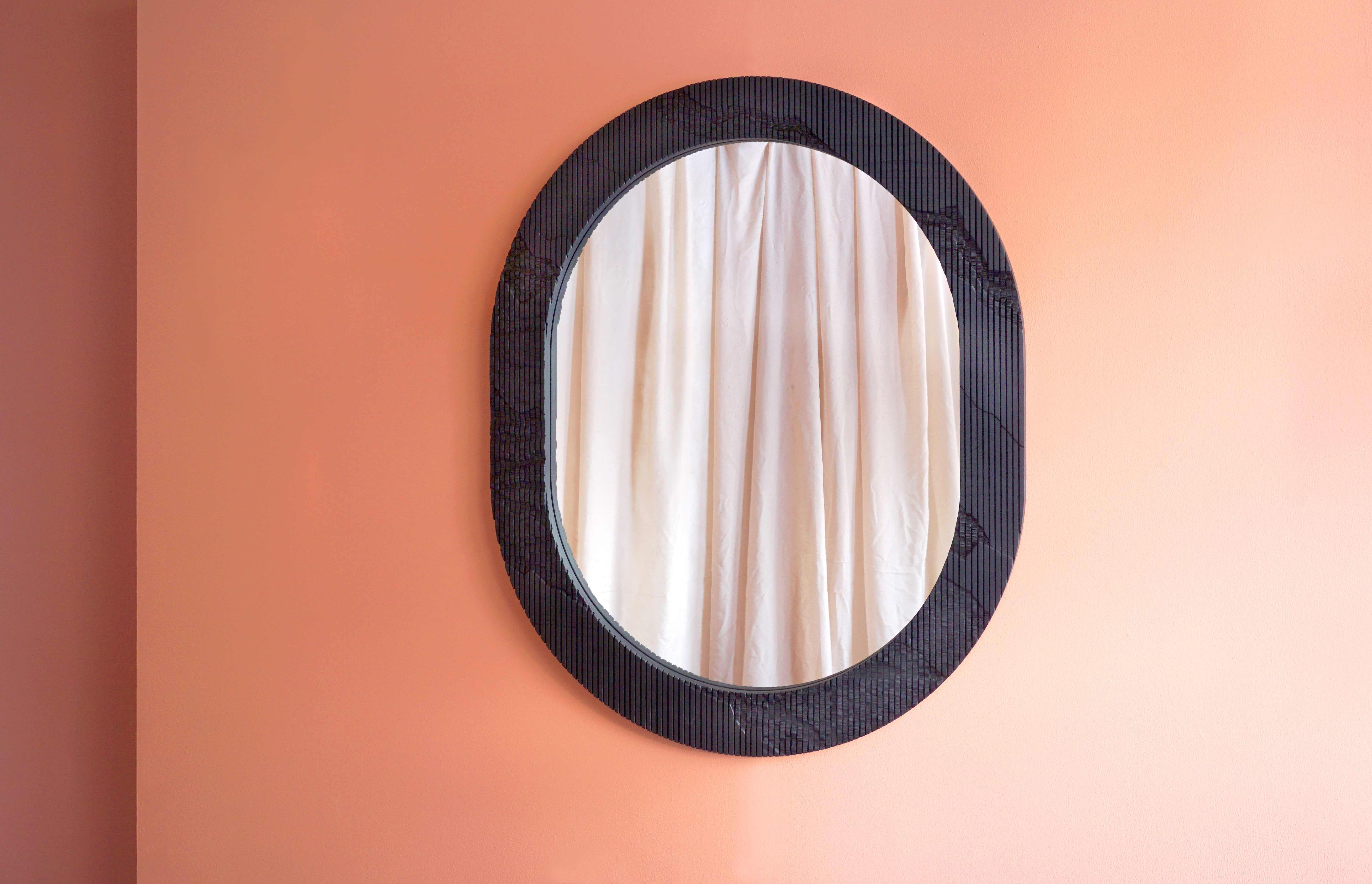 En apportant la sérénité de l'extérieur dans la maison, le miroir Shale a une texture distincte sculptée sur la surface du cadre qui semble aller au-delà de ses limites. La surface en frêne massif est rayée verticalement dans le sens du grain, et le