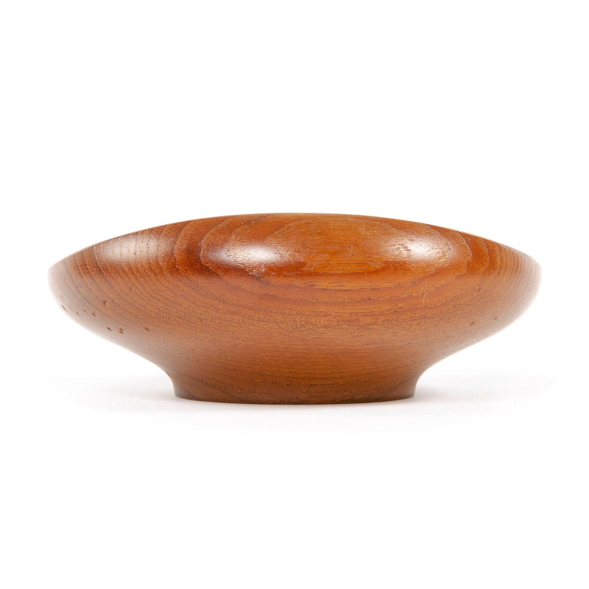 An sculptural hand turned footed teak bowl with vivid grain and a thick undulating rim.