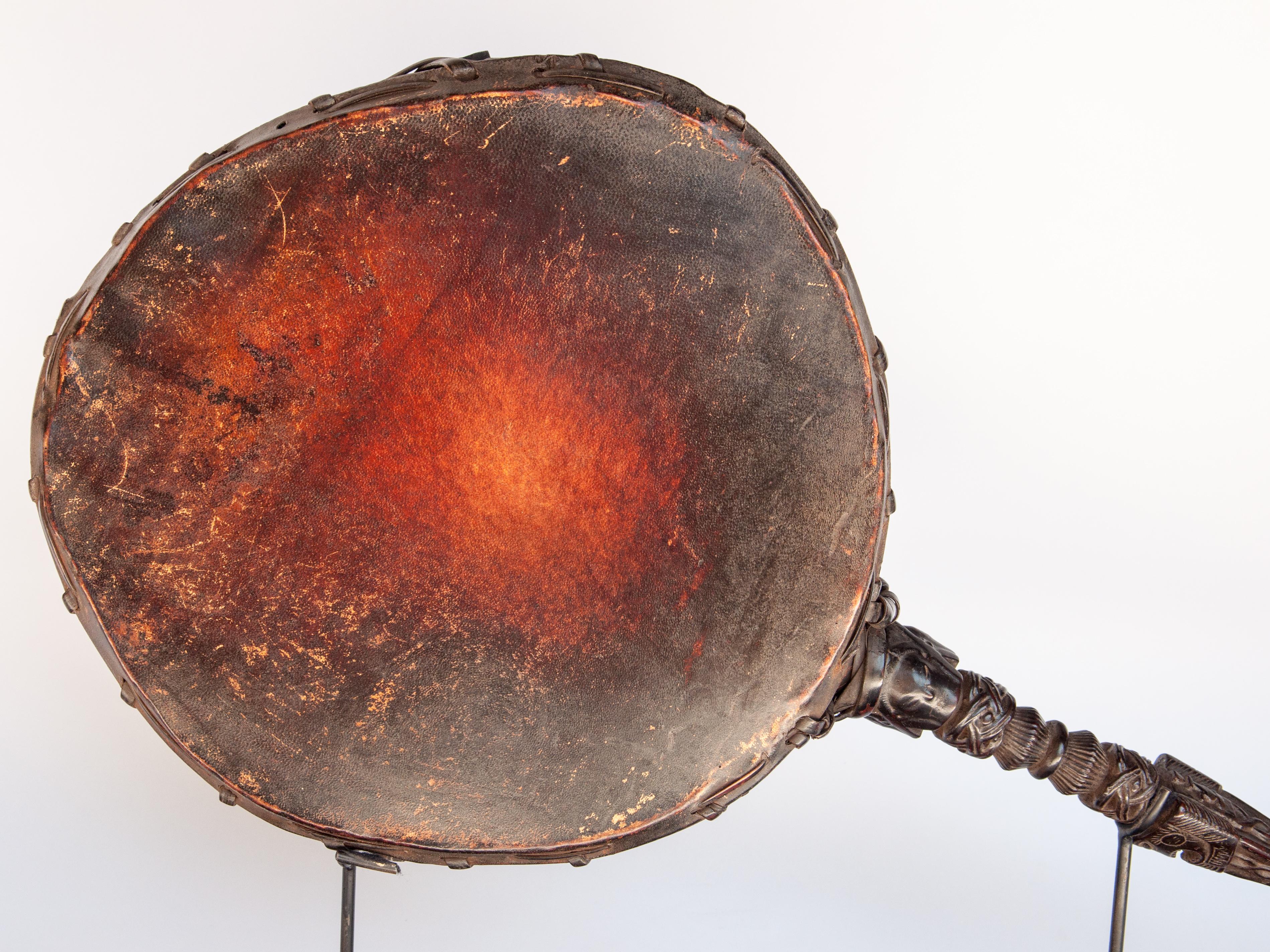 Vintage Shaman drum with carved wooden handle. Nepal Himalaya, mid-20th century. Mounted on a metal base.
Typical of the drums used by shamans in the Himalayan regions of central and east Nepal, this two sided drum has an extended handle akin to