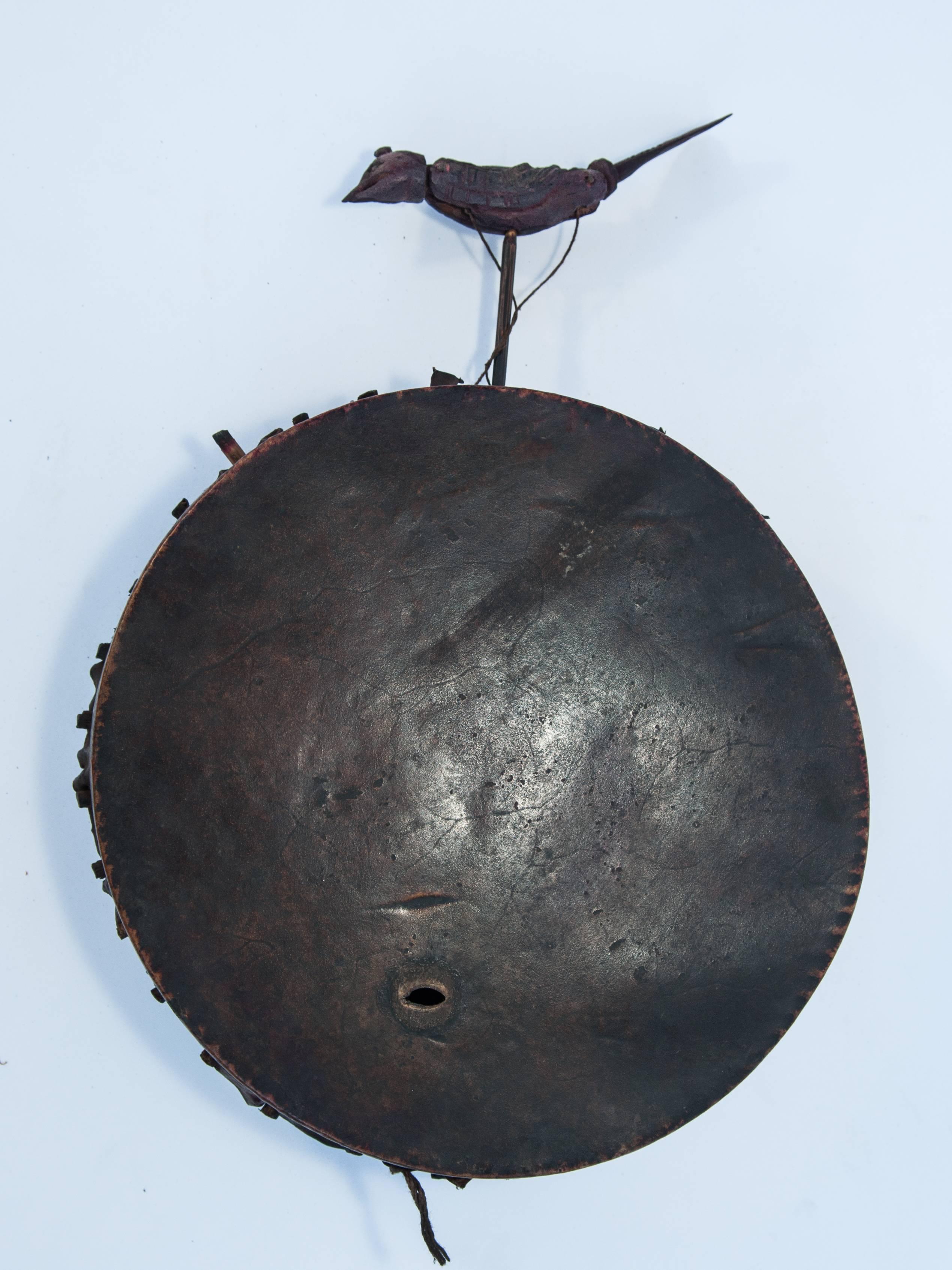 Shaman drum with carved bird. From Nepal, mid-20th century.
Fashioned by hand with the unusual feature of an articulated bird extending from the top of the drum. There is a single and very old hole in the face of the hide. 
Dimensions: 10 inches by