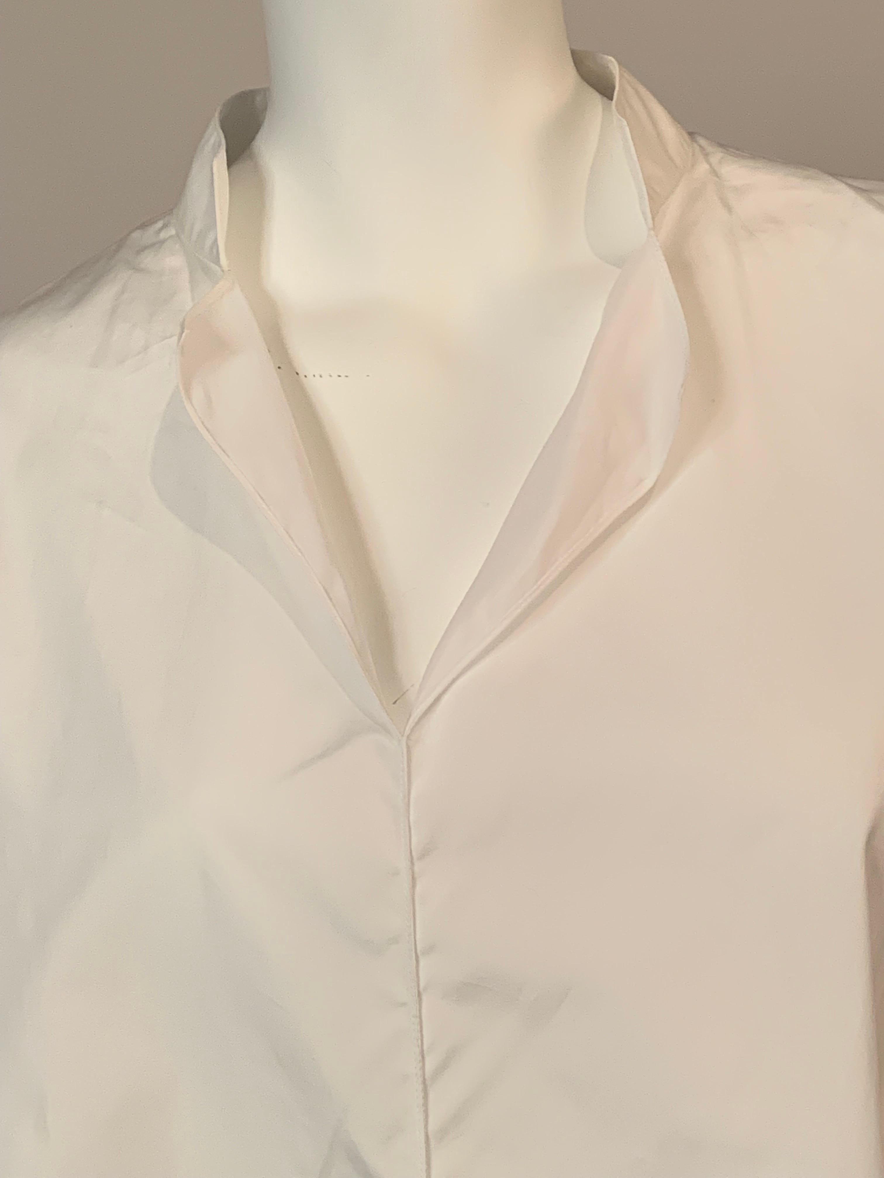 The perfect summer shirt, this oversized white cotton tunic slips on over your head. The front center seam is open at the neckline and hem for ease of movement. These openings are repeated on the side seams as well.
 The long sleeves can be rolled