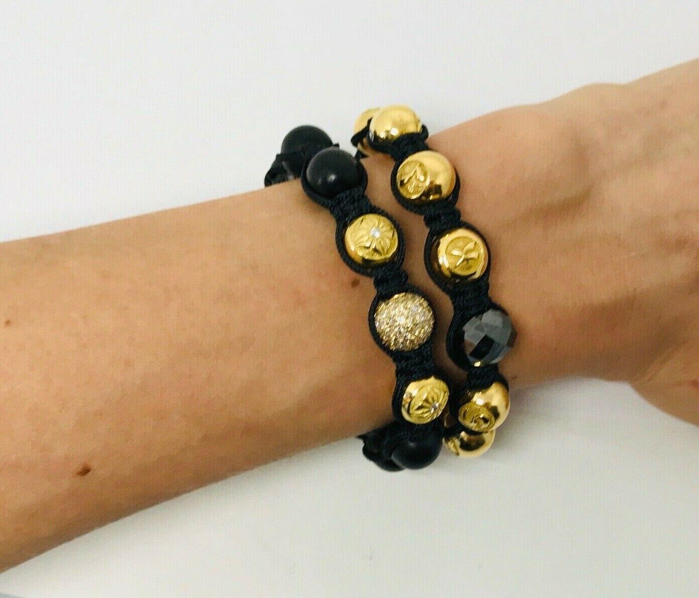 A pair of famous braided Shamballa Jewels bracelets. 
One bracelet features eleven 18k yellow gold beads (6 of them has G/VS diamonds), one black solid faceted diamond bead and a black Tahiti pearl bead. 
Another features 6 black wood beads, six 18k