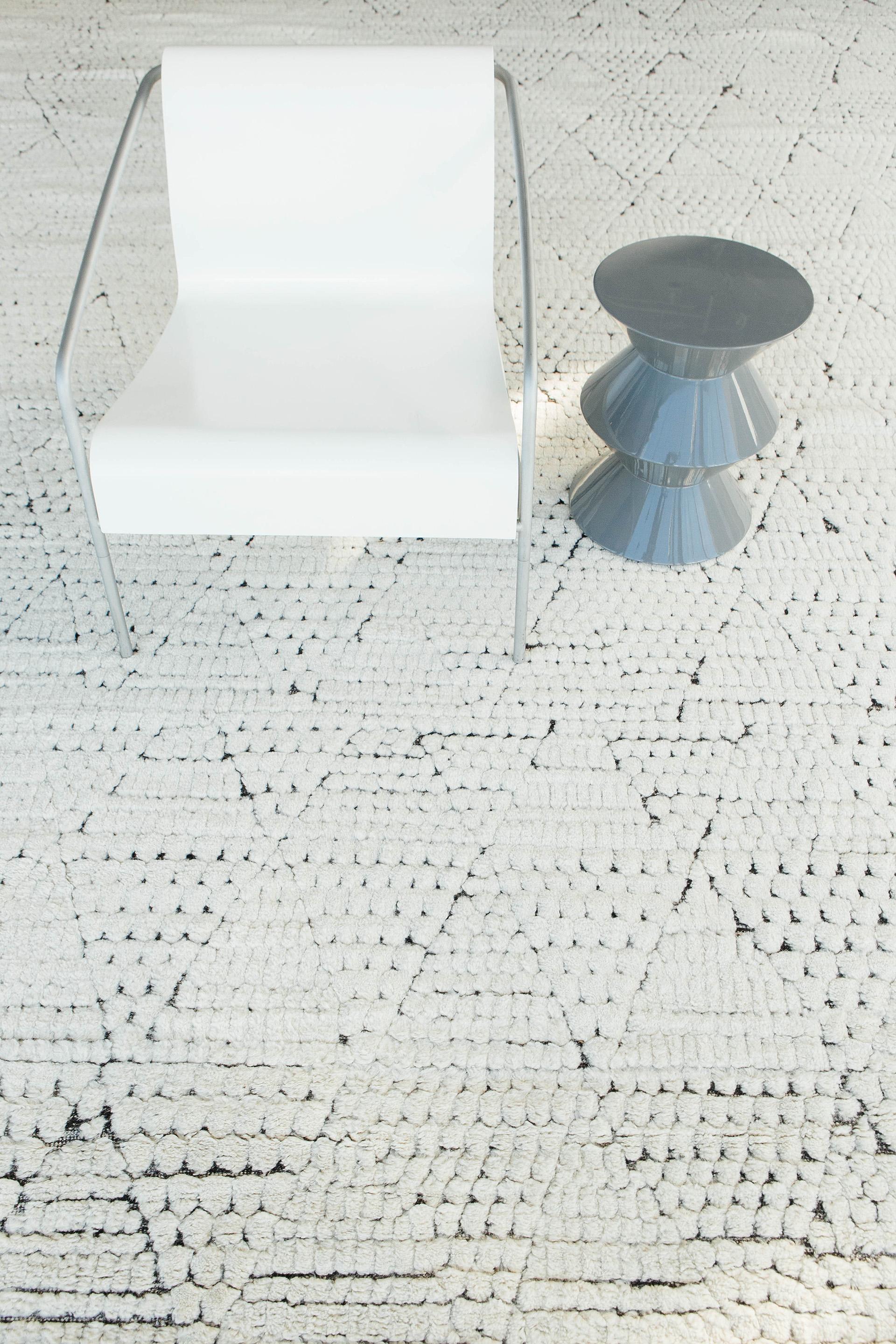 Shan is a beautifully textured rug inspired by the Atlas Mountains of Morocco. Off-white shag weaved into circular piles and embossed into triangles lattice throughout the piece creating a rug full of character. This piece designed in Los Angeles