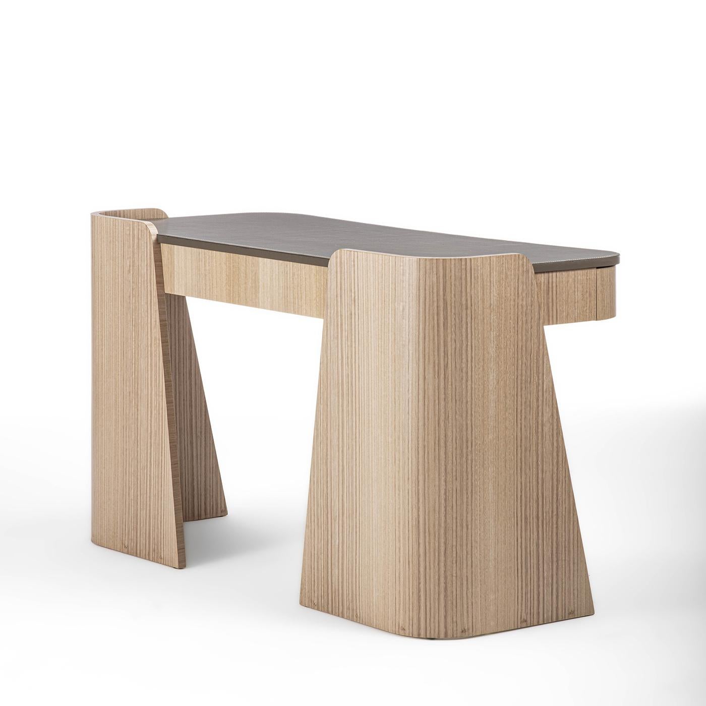 A sculptural silhouette defined by dynamic slanted cuts and enveloping curves marks this eye-catching desk from the Shape Collection. Offered in a luminous beige tone, the precious eucalyptus structure features two wide drawers sealed by a smooth
