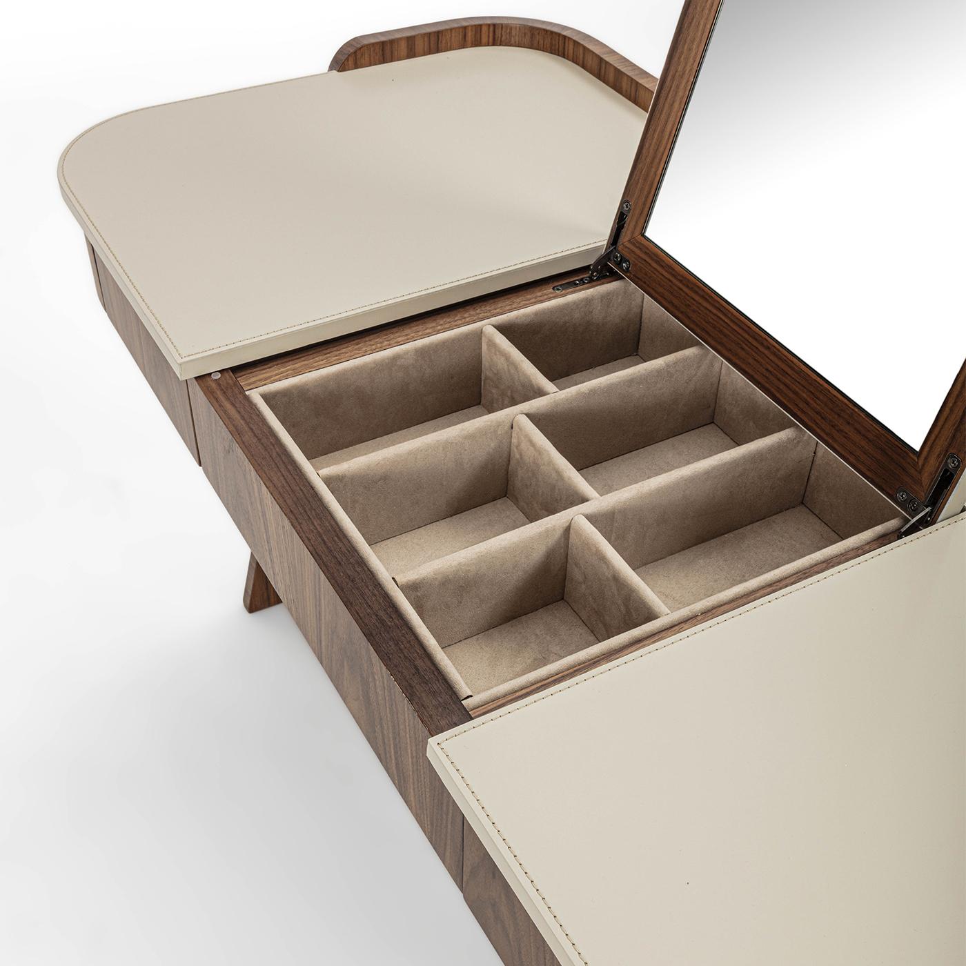 Owing its sculptural appeal to the pair of curved legs, this vanity desk by Giuseppe Carpanelli seduces with its warm Canaletto walnut finish accented with precious leather inserts. Two drawers flank the central microfiber-lined compartments, which