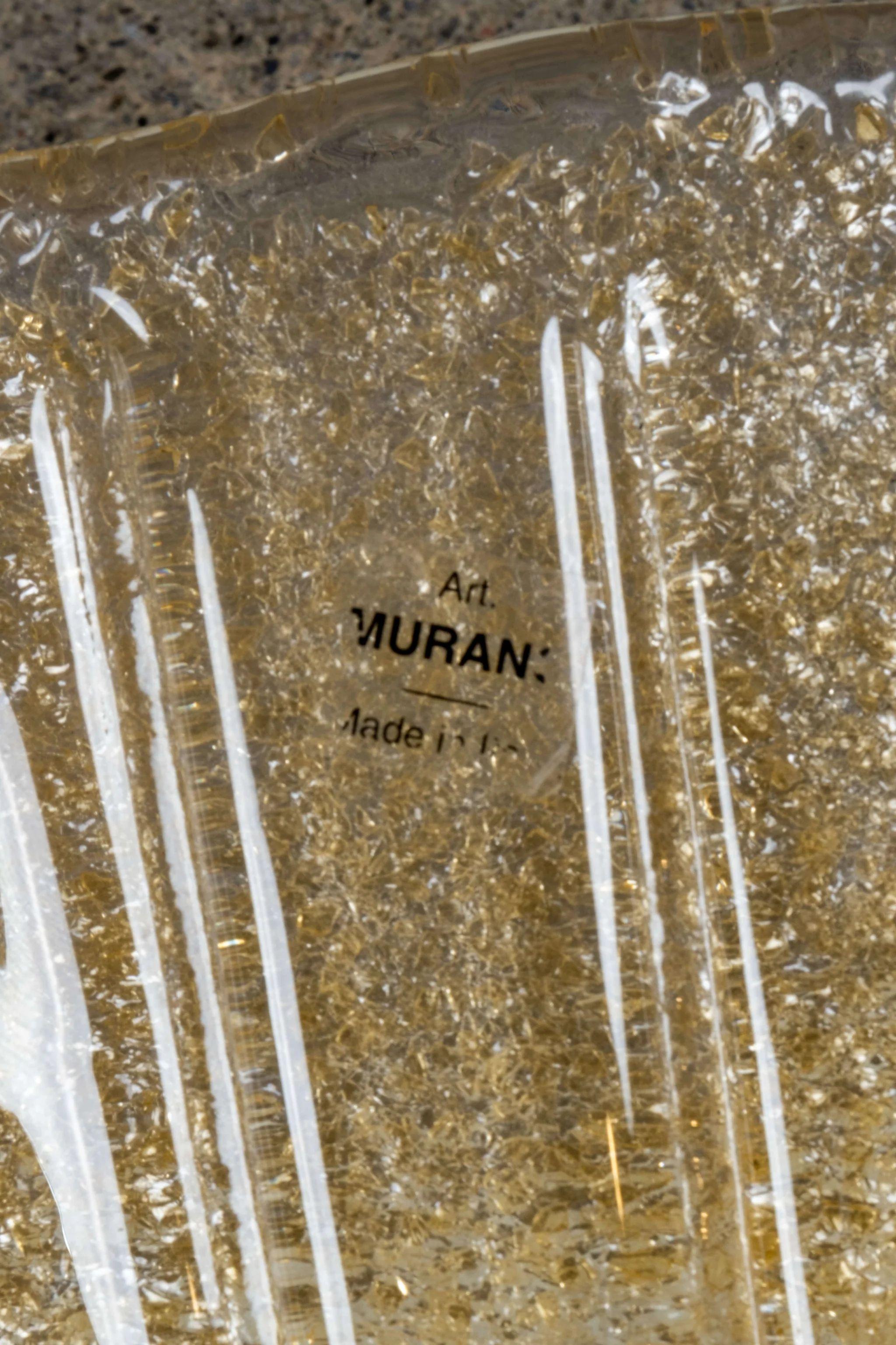 Los bellos apliques de cristal de Murano, de color ámbar, parecen prendidos con una puntilla dorada en la cintura. Los detalles acanalados del cristal aportan textura y el color proporciona la cantidad justa de brillo. Fabricado en Italia.