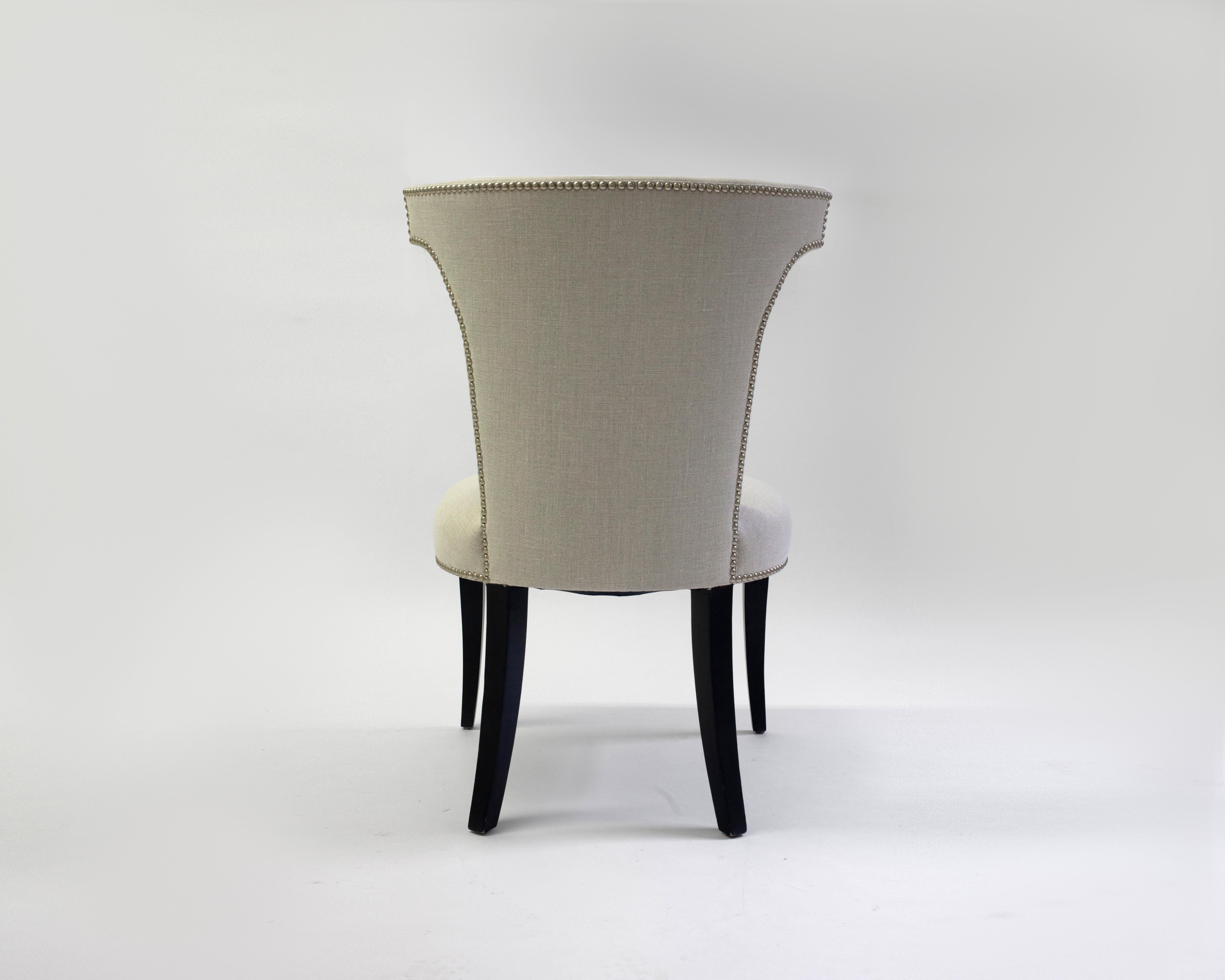 Der Menton-Stuhl ist ein wunderschön gestalteter Beistellstuhl in weißem Stoff mit selbst bezogenen Knöpfen an der Innenseite der Rückenlehne - Nagelkopfverzierungen unterstreichen die Anmut und die Linien dieses Stuhls - auf Holzbeinen in mittlerem