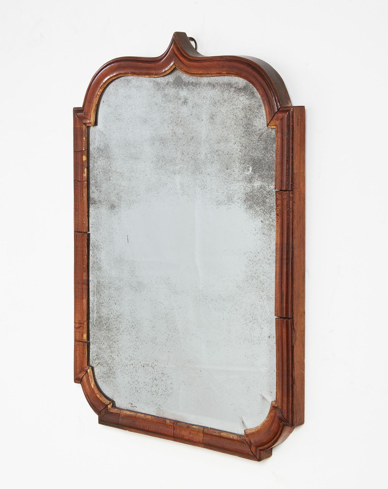 A wonderful early Queen Anne mirror circa 1705 having shaped and molded walnut frame with brace top and curved corners, and with rare original plate with shaped hand-beveled edge.  Attractive color and elegant form. 
