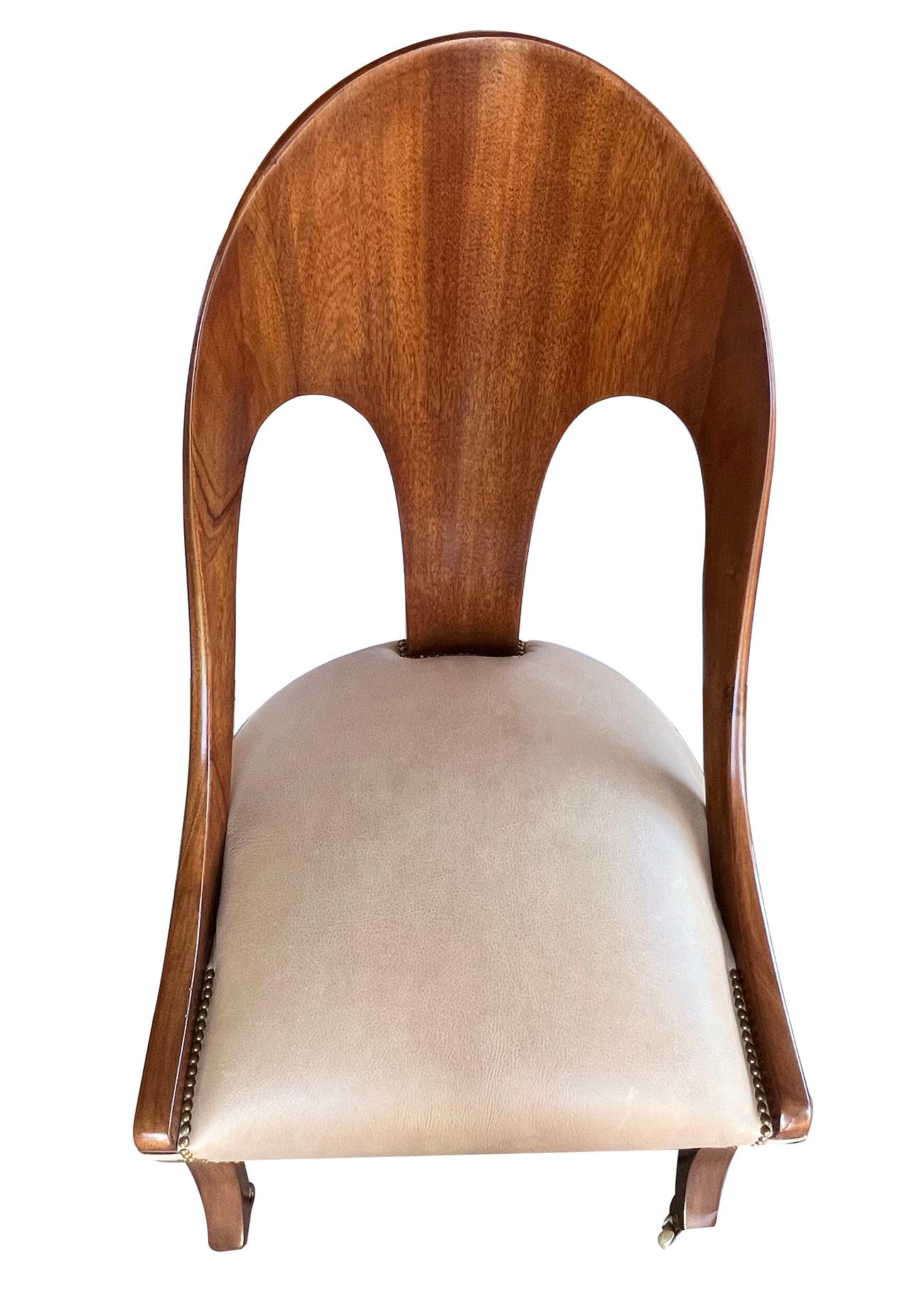 Of heavy solid mahogany construction with in-curved arching back sloping down to a tight seat all raised on splayed supports ending in brass casters.