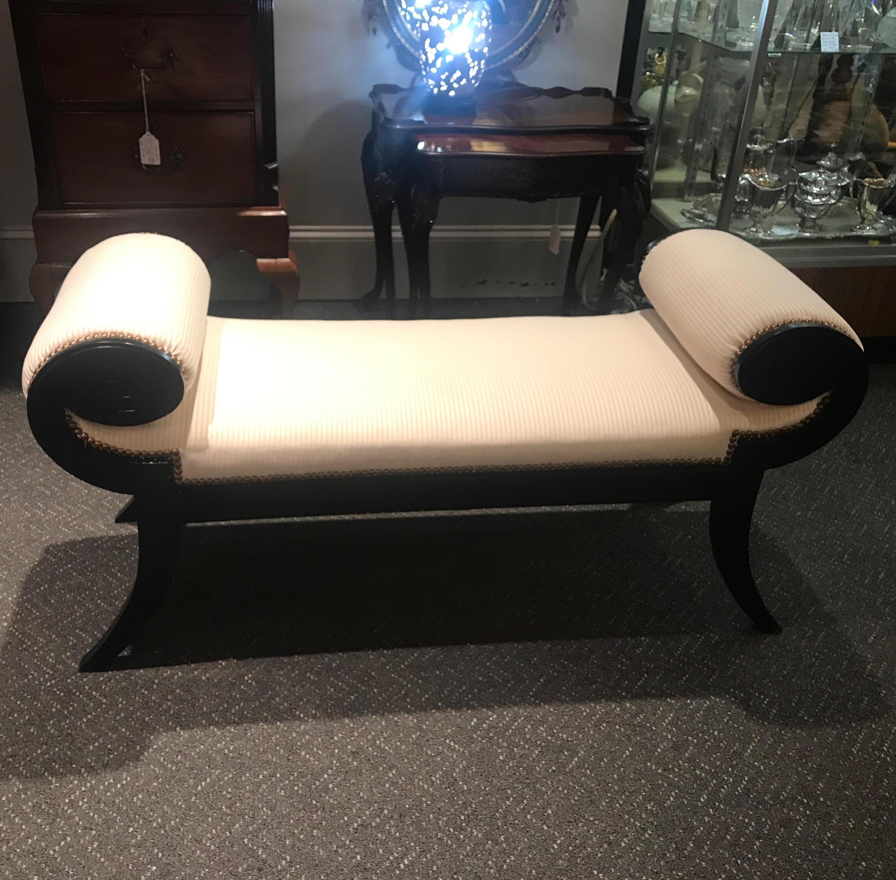 High style and chic Hollywood Regency bench with black lacquered frame and off white oyster tone fabric. The rolled arms with upholstery and upholstered seat resting on for flared legs.