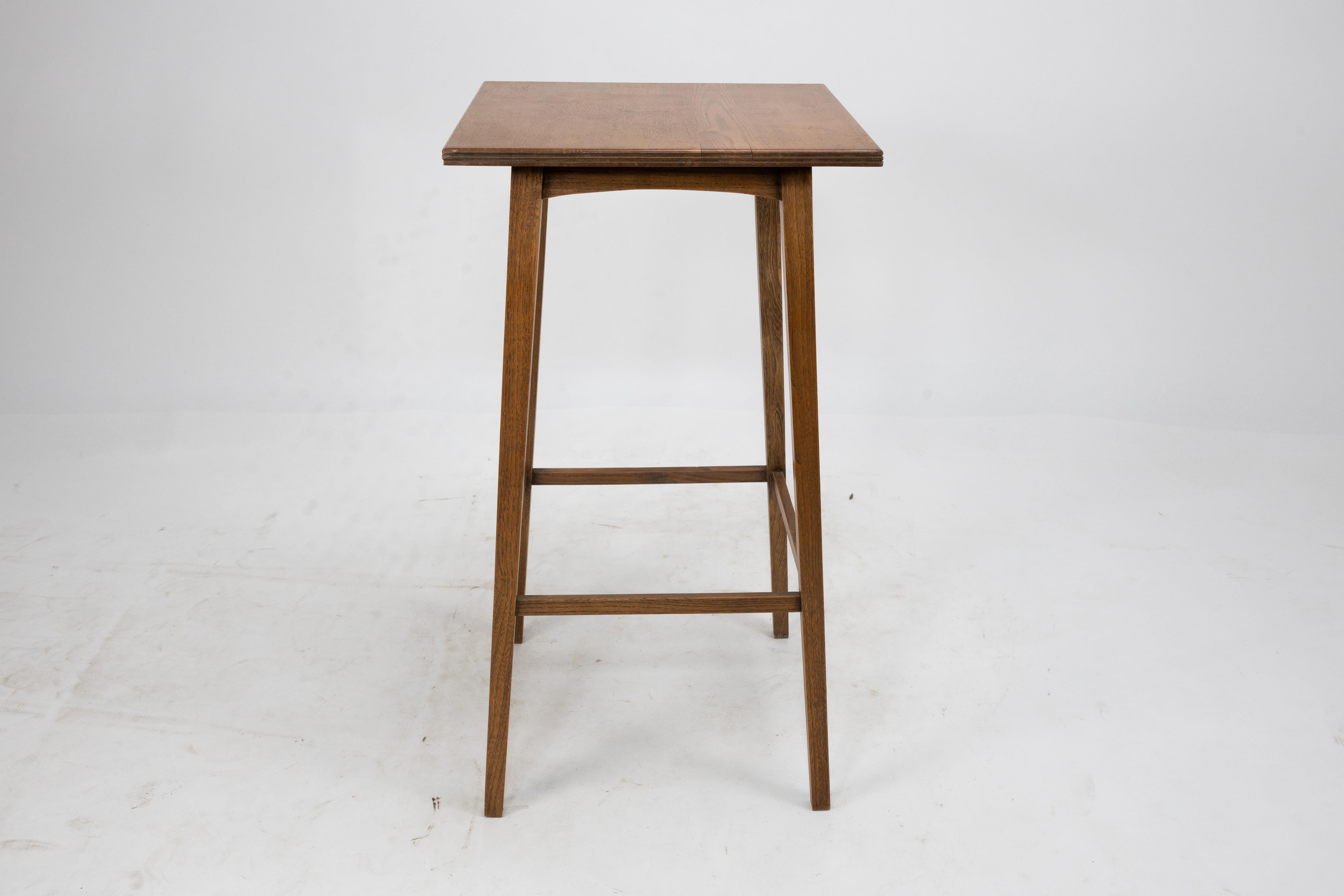 Shapland and Petter of Barnstaple. A small Arts and Crafts Ash side table with a moulded edge to the wild grain top with arched aprons below on fine slender tapering legs united by stretchers.
