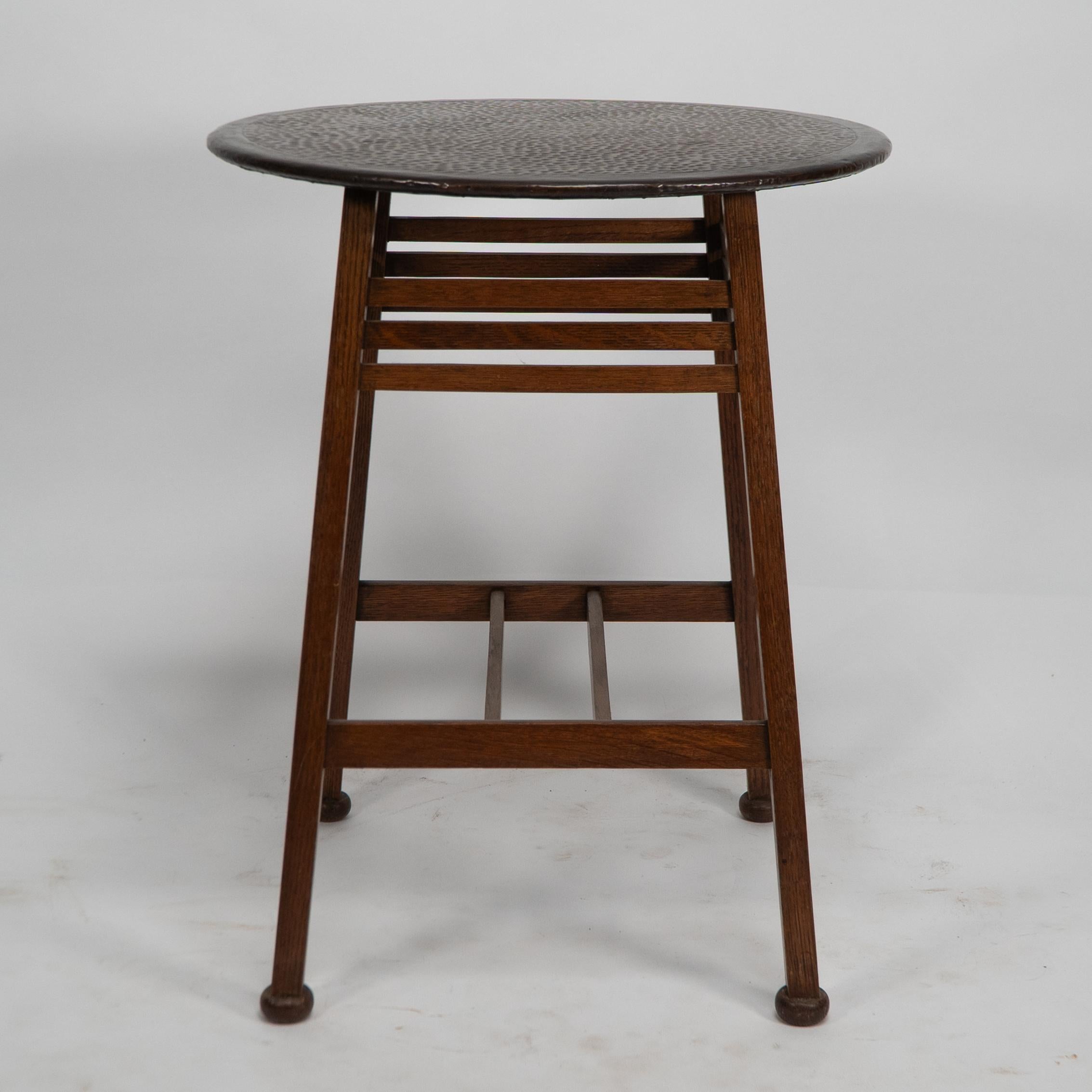 Shapland and Petter. An Arts and Crafts oak side table with a hammered copper top, the legs with applied squashed ball feet are united by three upper horizontal supports and a twin H stretcher.