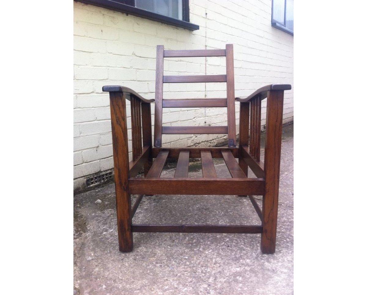 Shapland and Petter, attributed.
A stylish Arts and Crafts oak reclining armchair with shaped extended arms and slatted sides, waxed and ready for cushion upholstery.