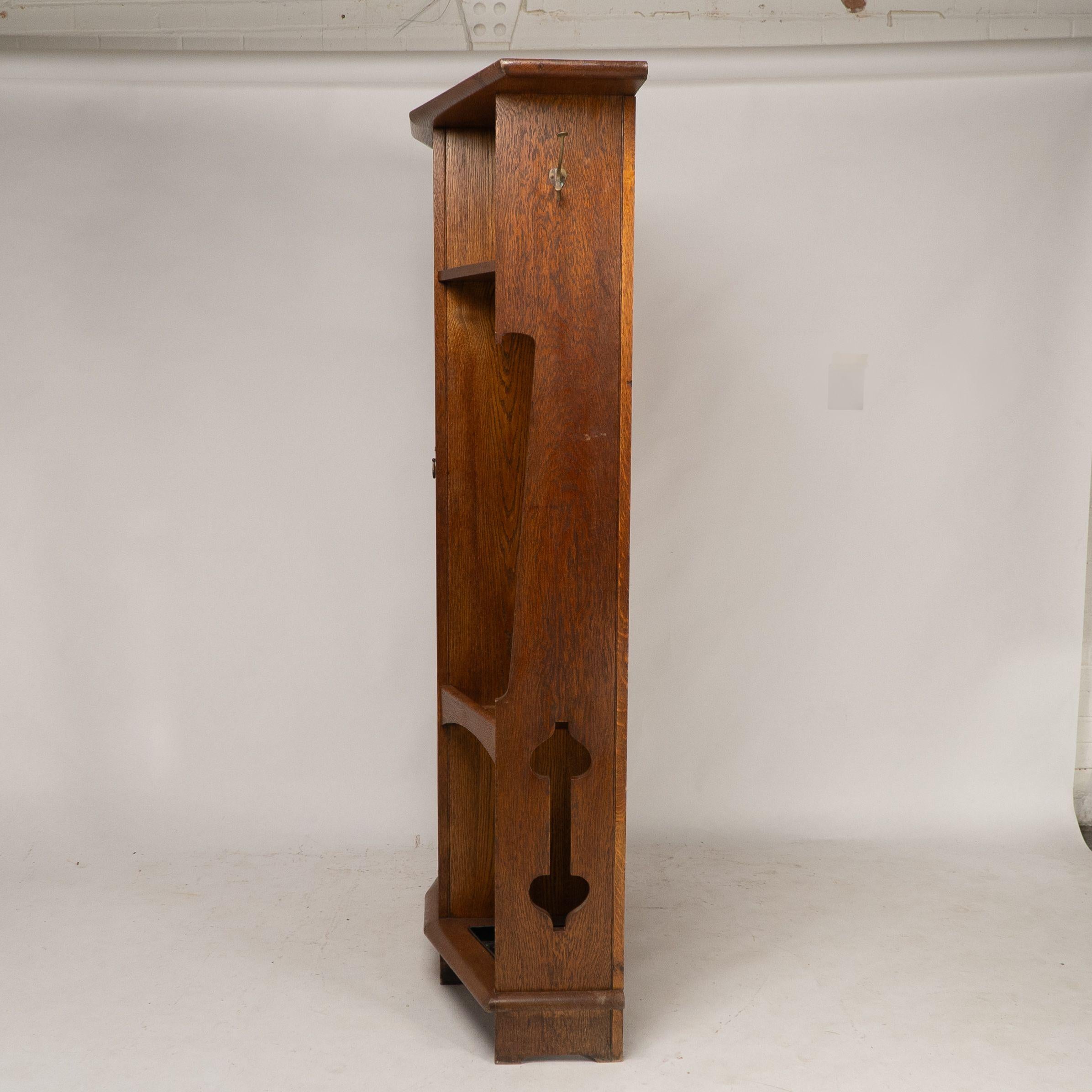 English Shapland & Petter attri. An Arts & Crafts oak hall cupboard with flaring cornice For Sale