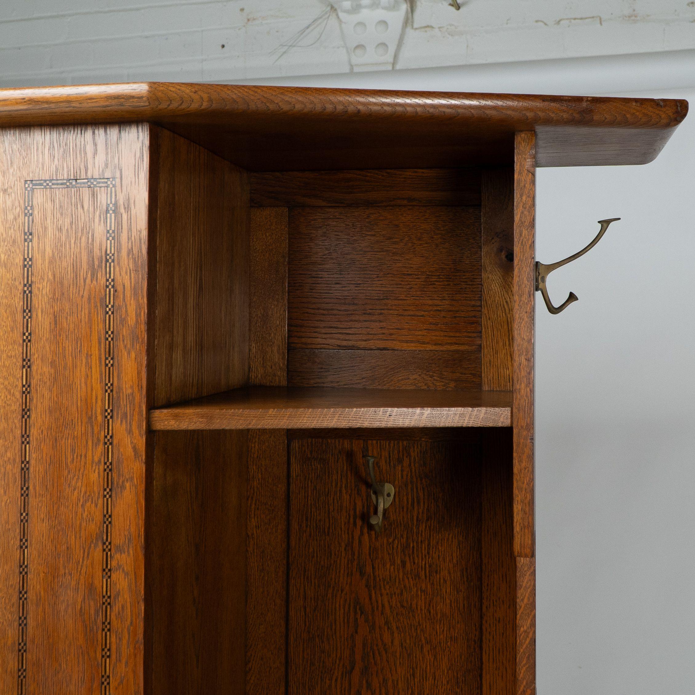 Copper Shapland & Petter attri. An Arts & Crafts oak hall cupboard with flaring cornice For Sale