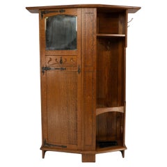 Shapland & Petter attri. An Arts & Crafts oak hall cupboard with flaring cornice
