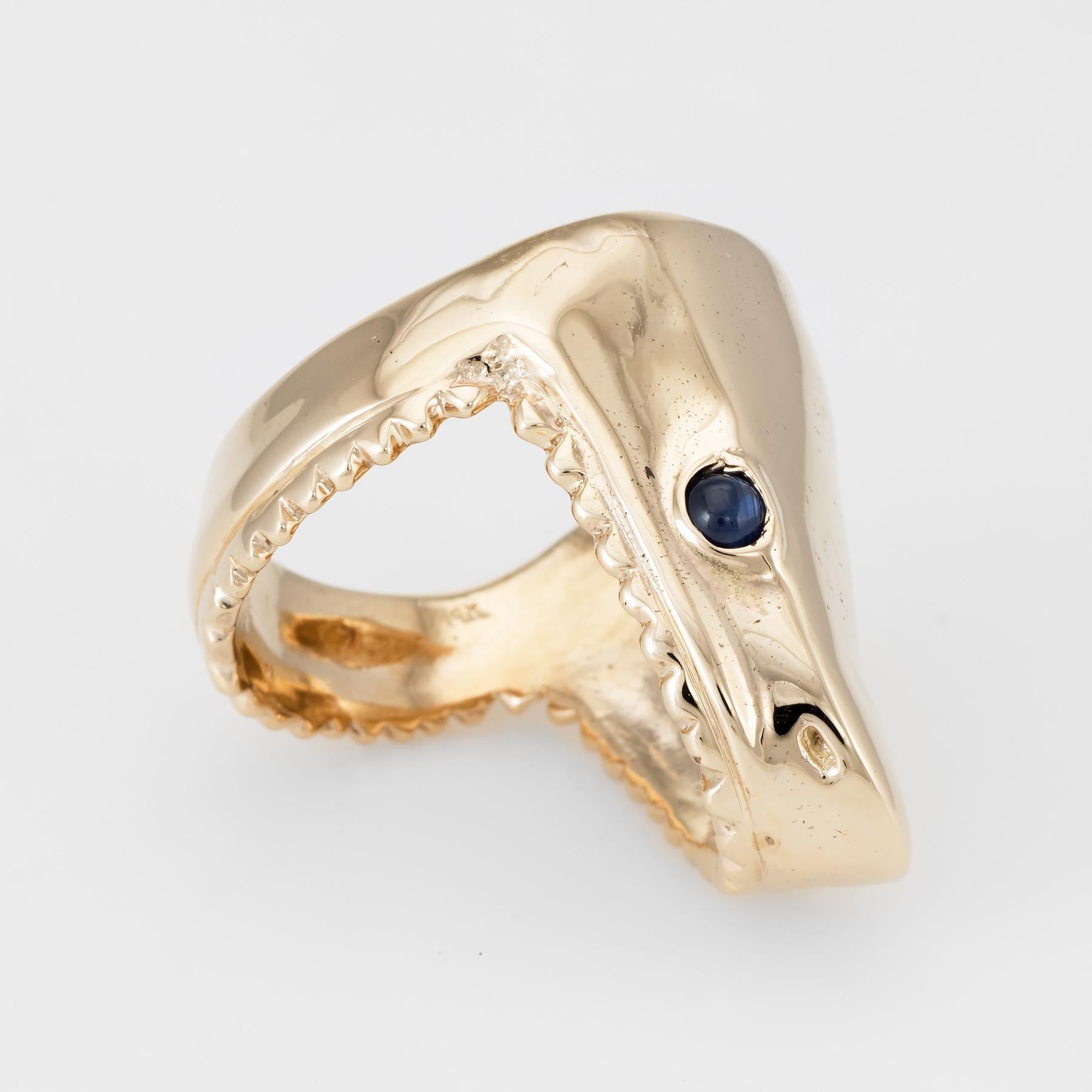 Distinct and unusual shark head ring, crafted in 14 karat yellow gold. 

Two x 3mm cabochon cut blue sapphires are set into the eyes (note: slight chip to one sapphire - visible under a 10x loupe).   

The ring is in very good condition.