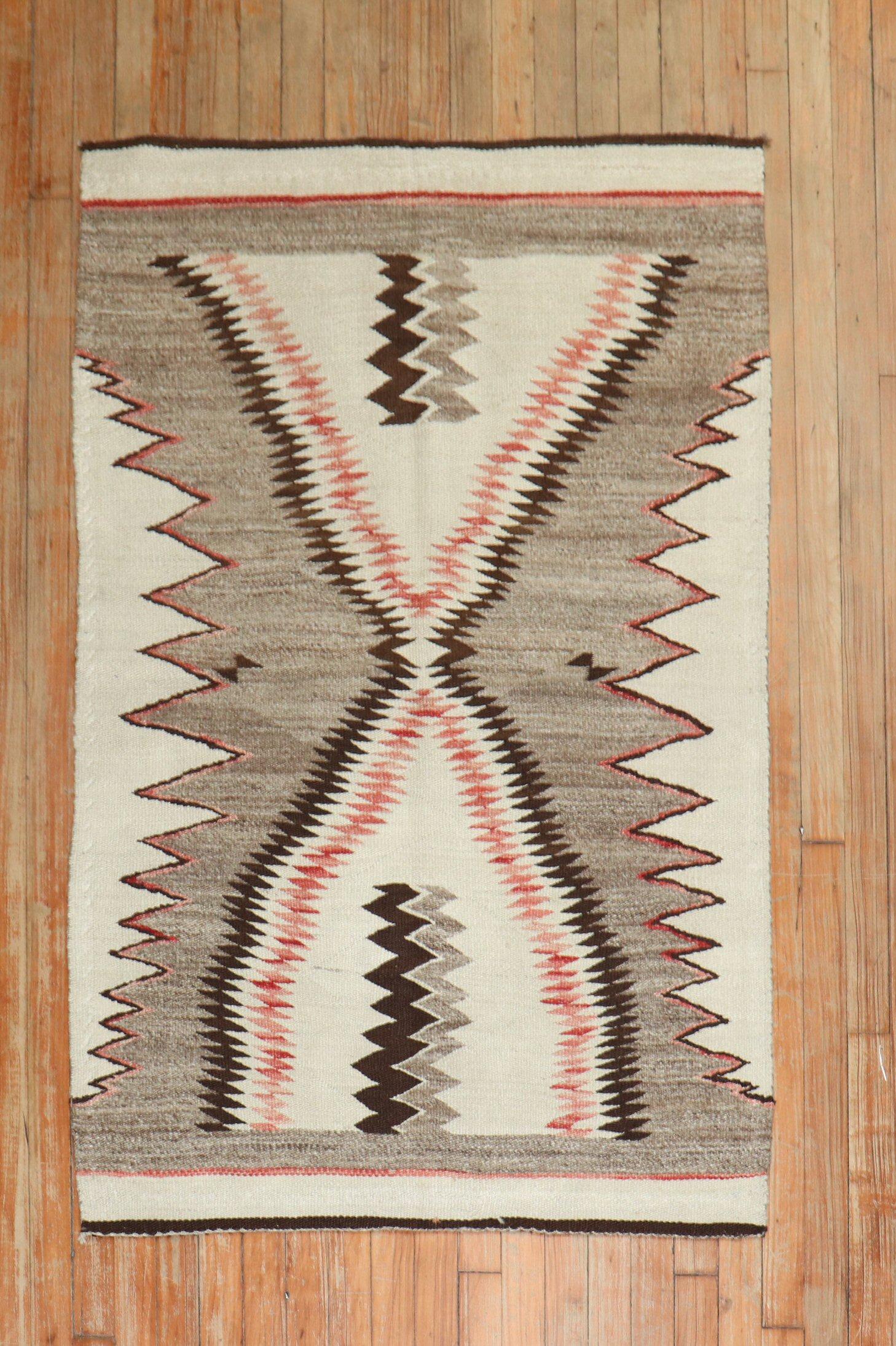 An early 20th-century high-decorative American Navajo rug featuring a pattern resembling a sharks tooth in gray, ivory and coral

Measures: 3'1