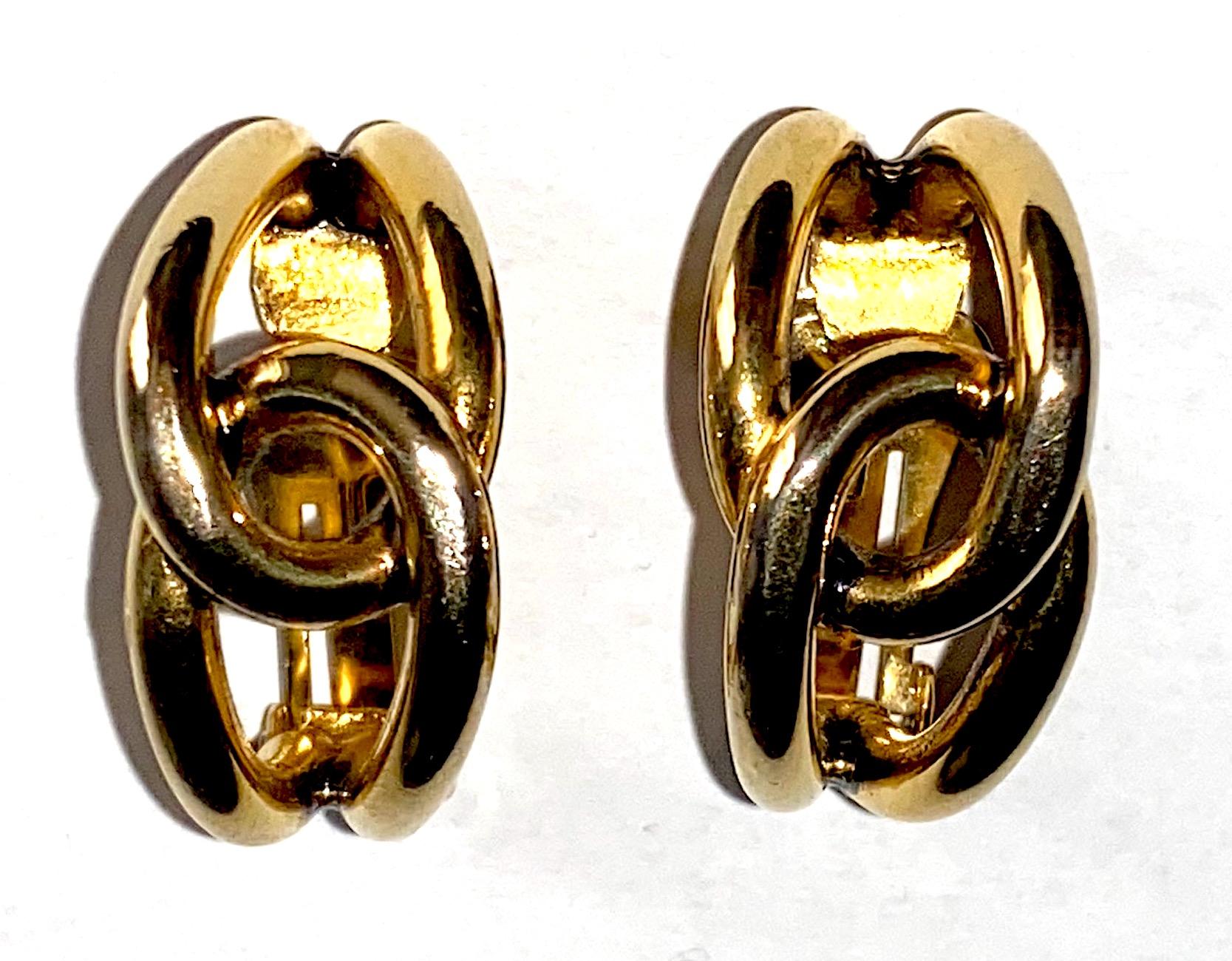 An elegant pair of hoop earrings designed by fashion jewelry designer Sharra Pagano of Milan, Italy. The gold plate hoops consist of two looped round wires that interlock in the center and taper at the ends. Each of the clip earrings measure .63 of