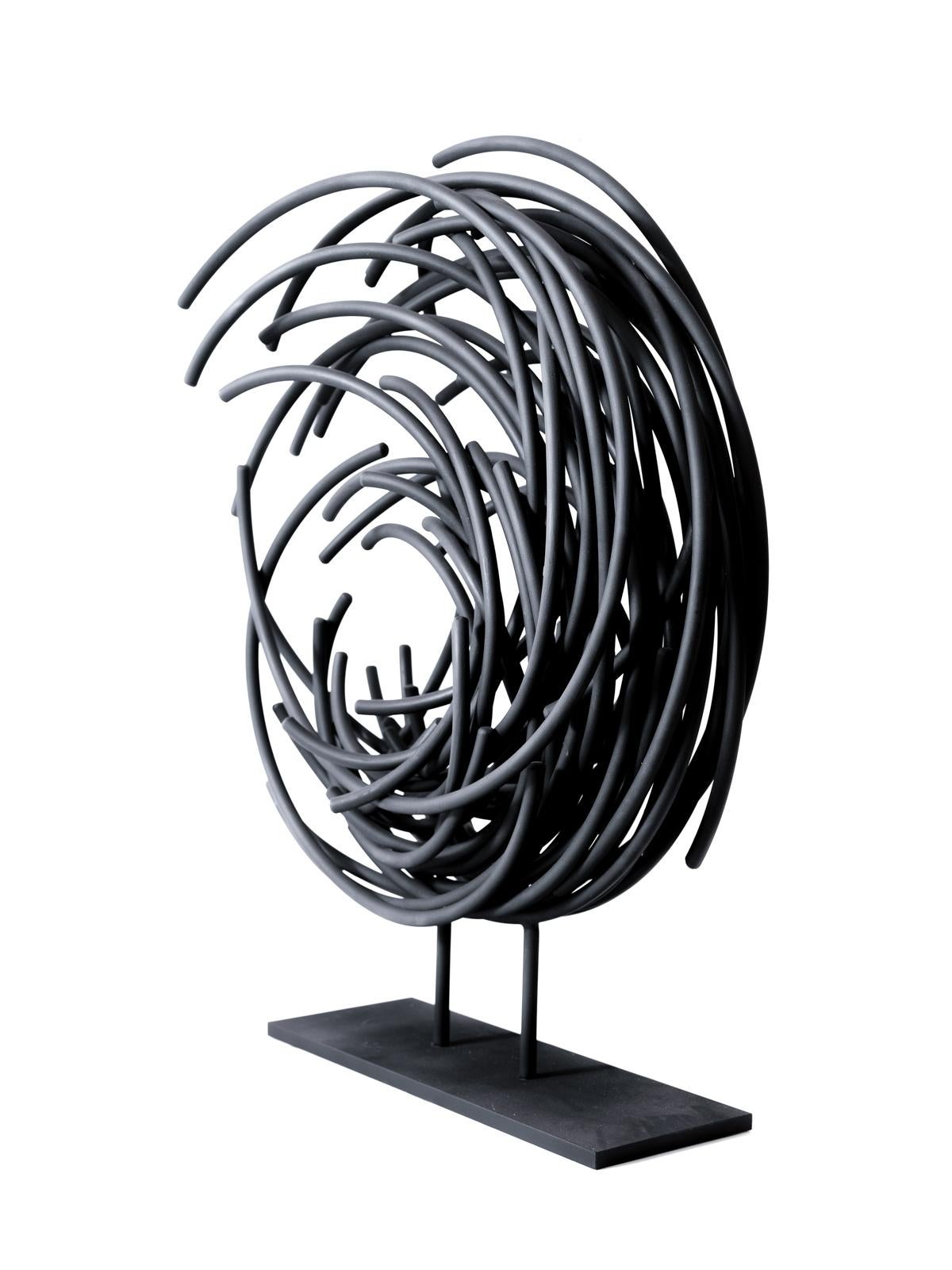 In jet matte black, this dynamic sculpture by Shayne Dark is part of an exciting new series called Maelstrom. Known for his uniquely beautiful abstract work, this piece is hand forged from small round aluminum rods formed into a circular shape that
