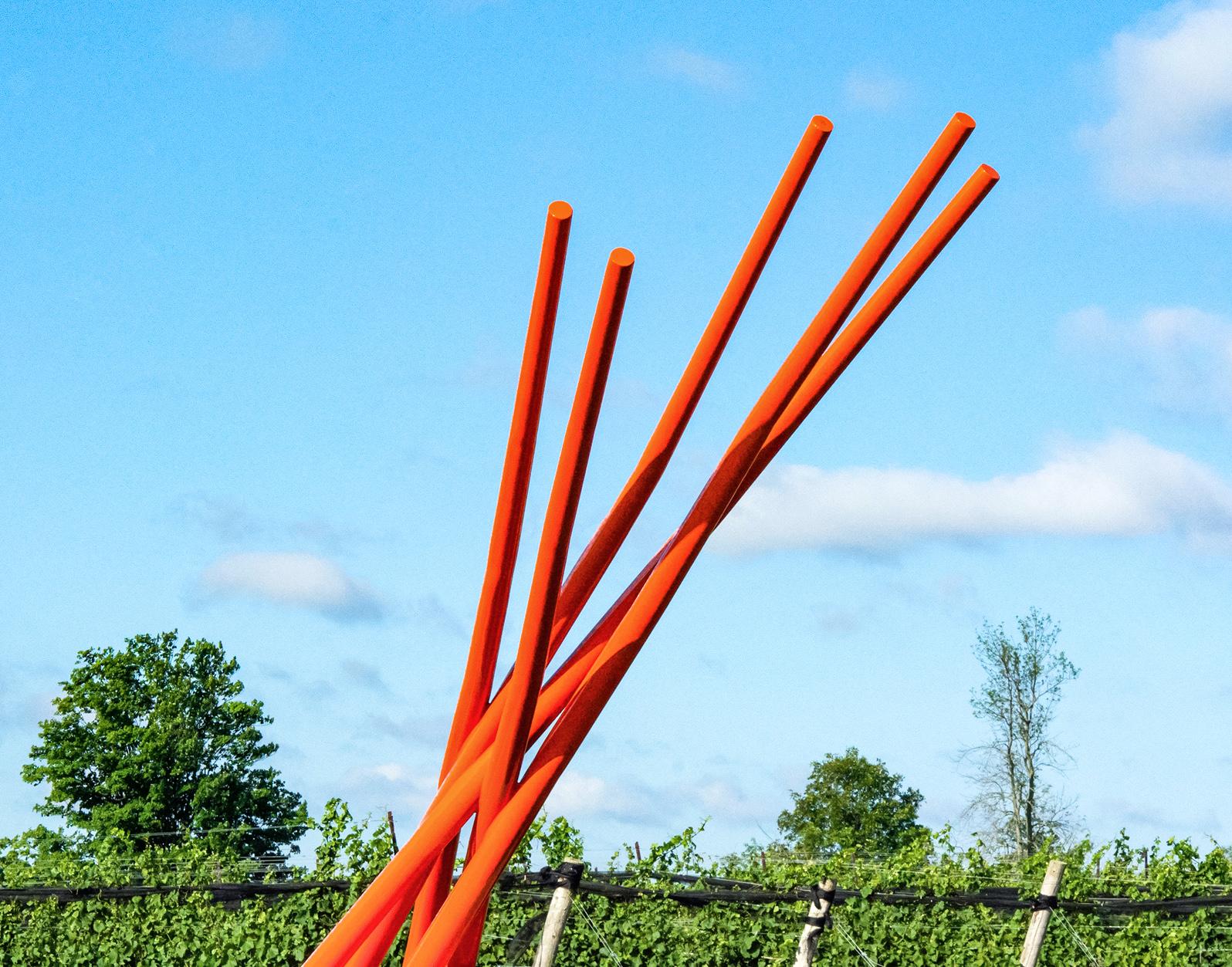 This contemporary orange-colored metal outdoor sculpture is the work of Shayne Dark. 

Five tapered shafts of steel emerge from the base in a powerful contemporary composition. The Canadian sculptor is known for using industrial materials to create