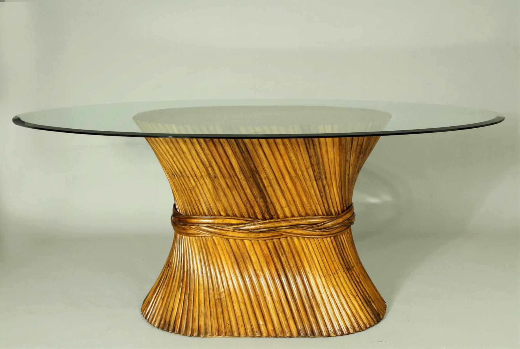 Sheaf of wheat table with glass top from the 1970s. The base is formed with bundled reeds with a woven band surrounding the center. The base supports a much larger glass top. Unmarked. This table is in very good condition.