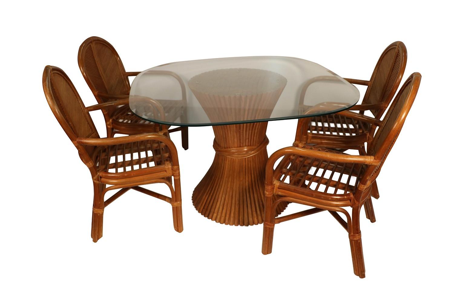 A stunning Rattan dining set in the style of McGuire Furniture. Features beveled edge square glass tabletop with rounded corners resting on round sheaf of wheat style rattan base, beautifully paired with four matching chairs, each with off white