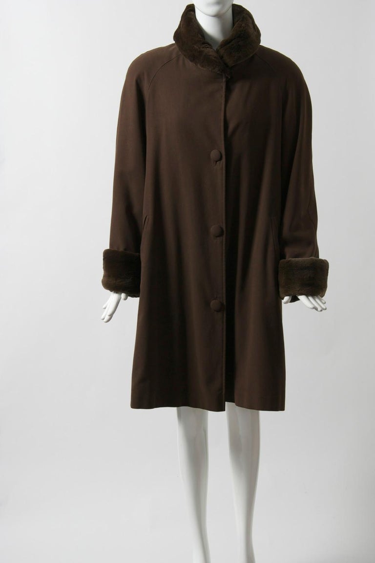 Custom-made coat featuring a sheared mink lining, collar, and cuffs. Outer fabric is brown, all-weather blend with bound buttonholes, self buttons, and diagonal slash pockets. Semi-swing style with dolman sleeves allows for sweater or jacket