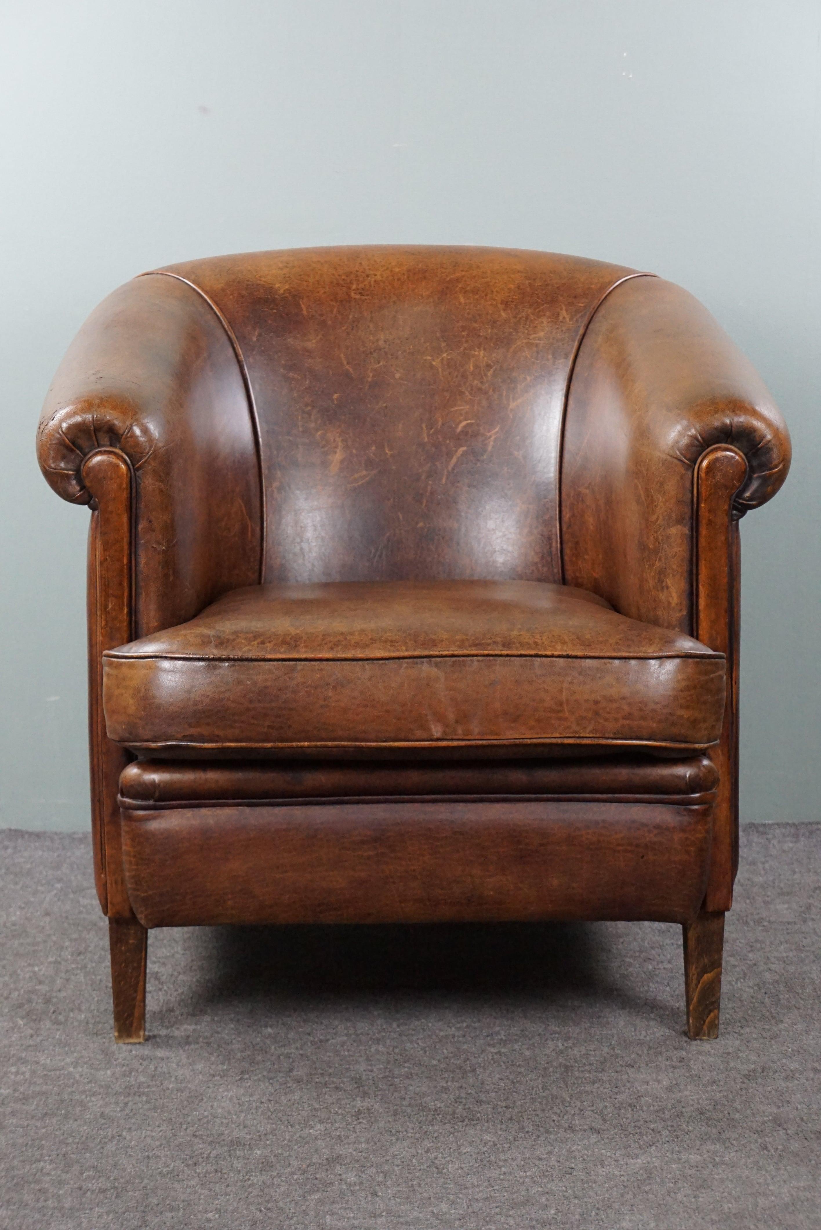 Offered is this beautifully subtly aged sheep leather club armchair finished with a matching tone piping. This incredibly delightful and comfortable sheep leather club armchair has acquired a lovely patina through responsible use. By using a