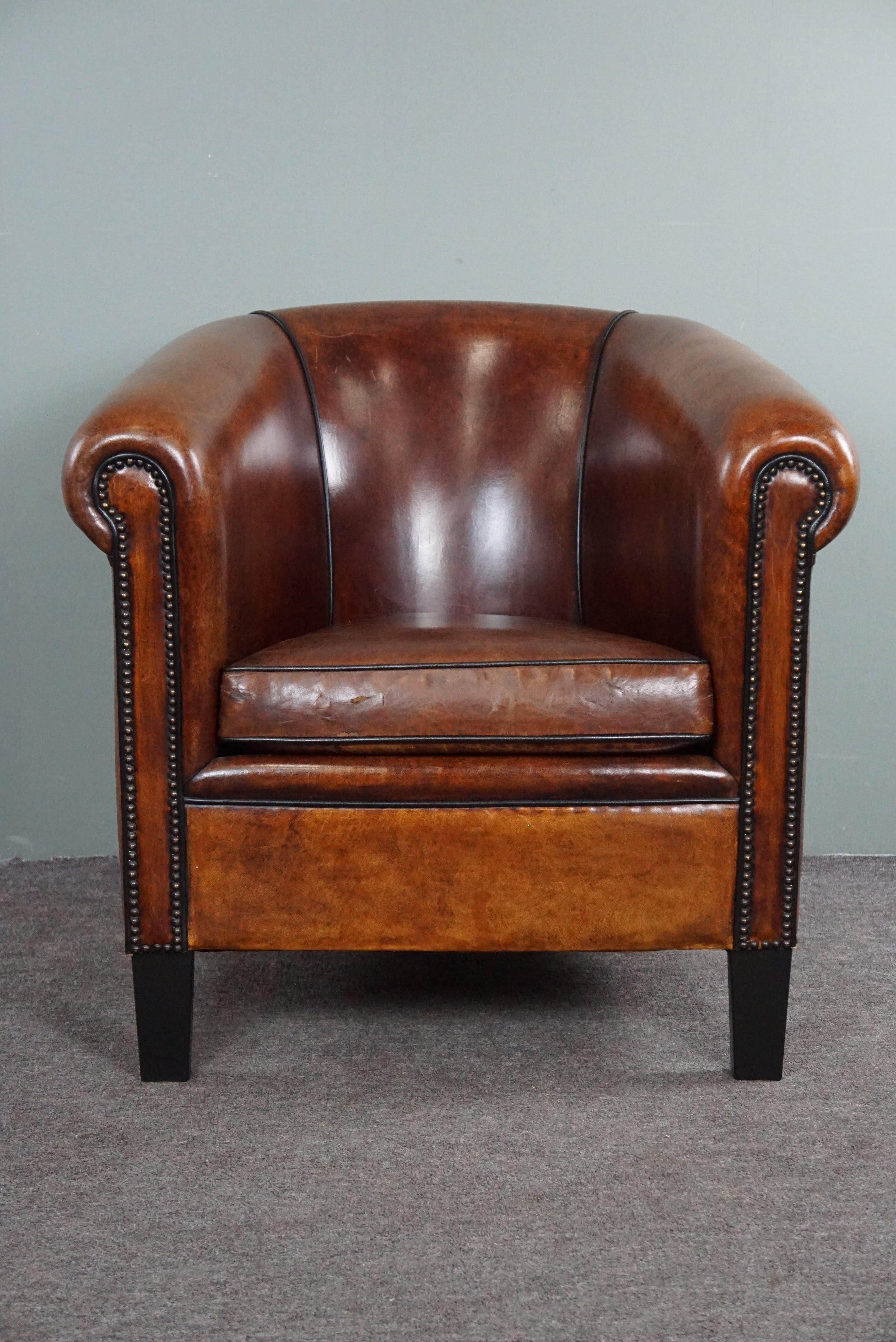 Offered is this warm-colored sheep leather club chair made with only top materials.

This sheep leather club chair is elegant because of the black piping in combination with the decorative nails and the amazing color. In our opinion, the seating