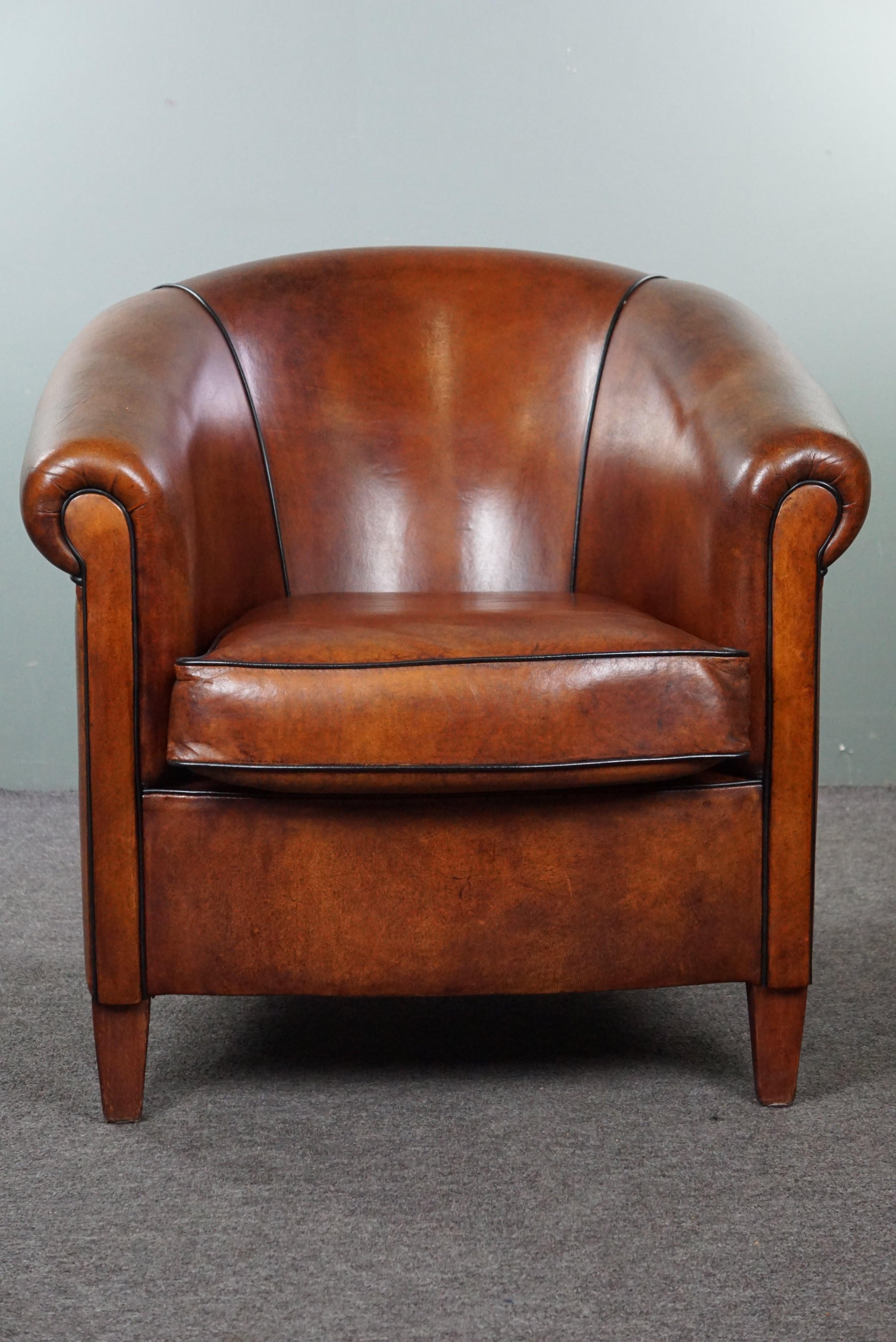 Offered is this beautiful, nearly new sheep leather club armchair with black piping. We consider a sheep leather club armchair to be the foundation of a timeless and sophisticated interior. While some individuals find an aged club armchair