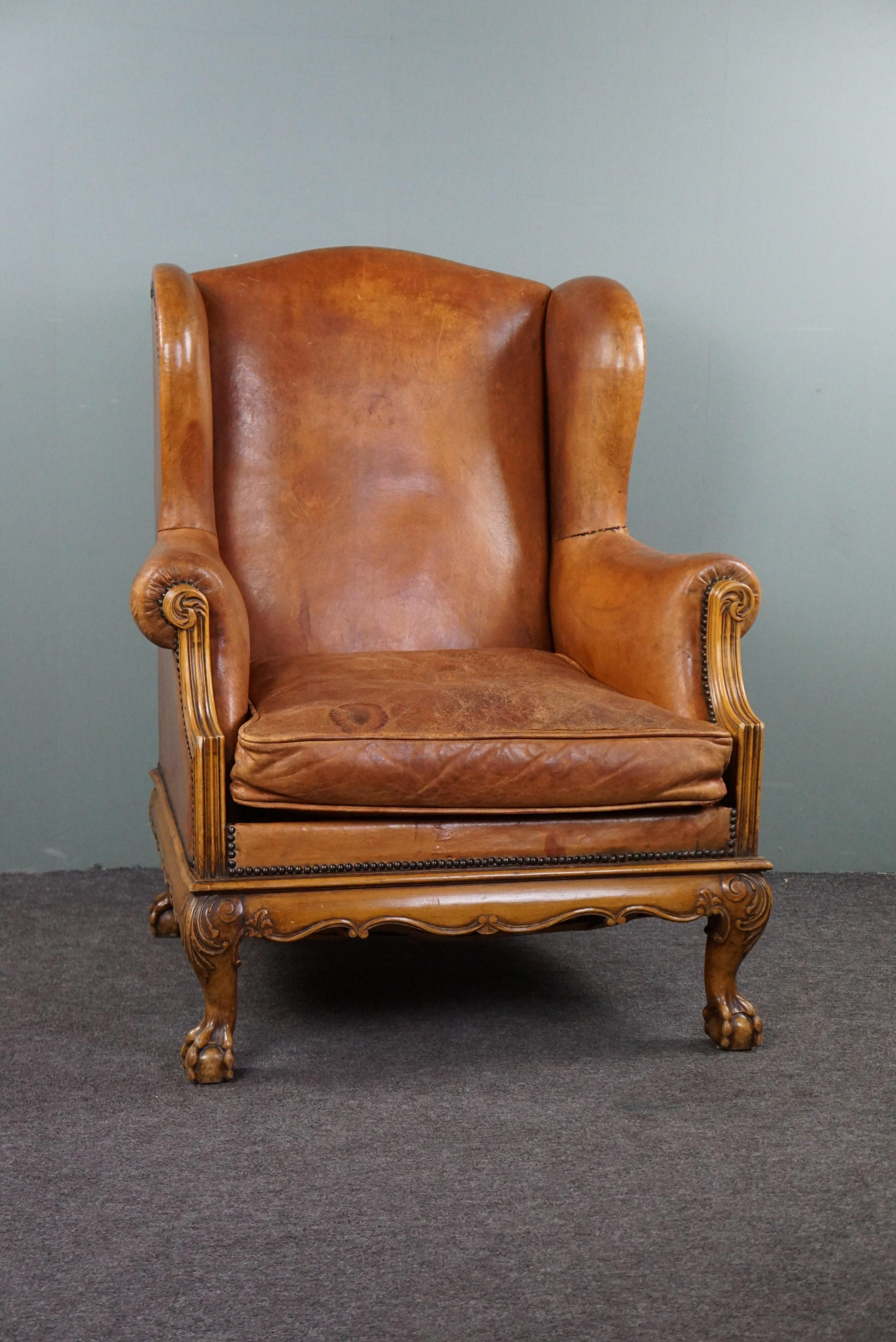 With pleasure, we offer you this characteristic sheep leather wing chair with graceful legs.

This sheep leather wing chair is set on a vividly decorated wooden base with beautifully carved claw feet. This chair not only provides character and