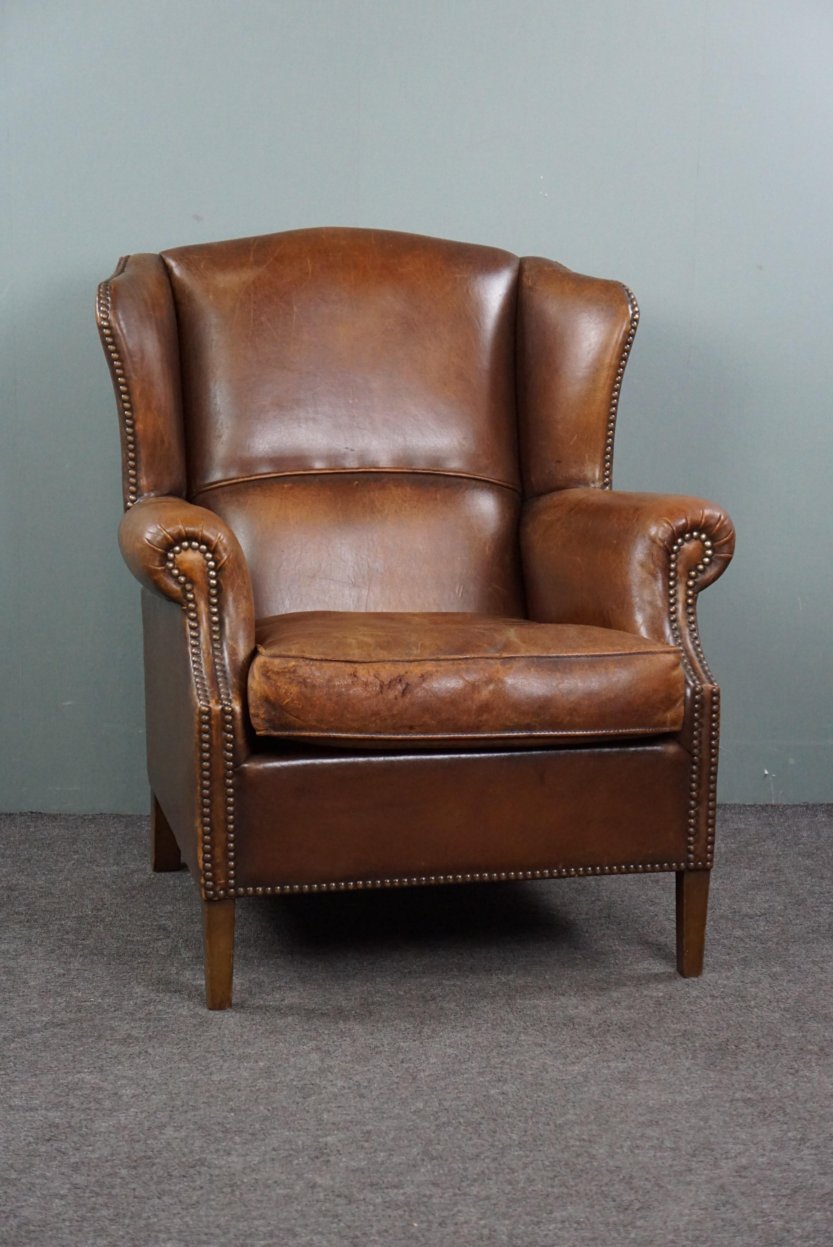Presented by ByThijs, this beautiful, warmly colored sheep leather wing chair adorned with elegant decorative nails.

This chair boasts a striking color and a beautiful patina. The subtle design and decorative nails make this item a chair that
