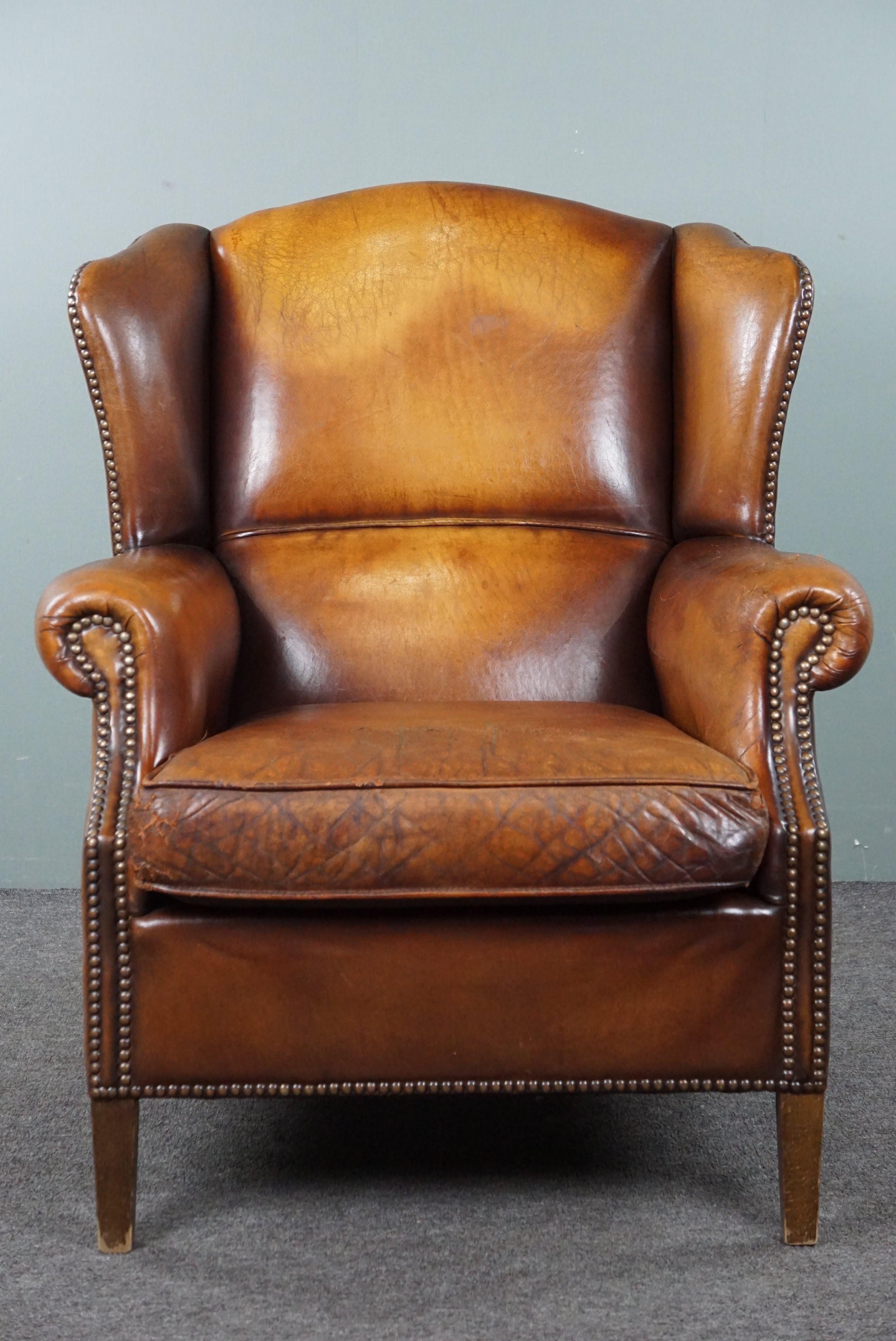 Offered is this striking sheep leather wingback chair. This sheep leather wingback chair is a positively striking item with a distinctive appearance. Thanks to its beautifully aged leather and timeless charm, this is a chair that many enthusiasts