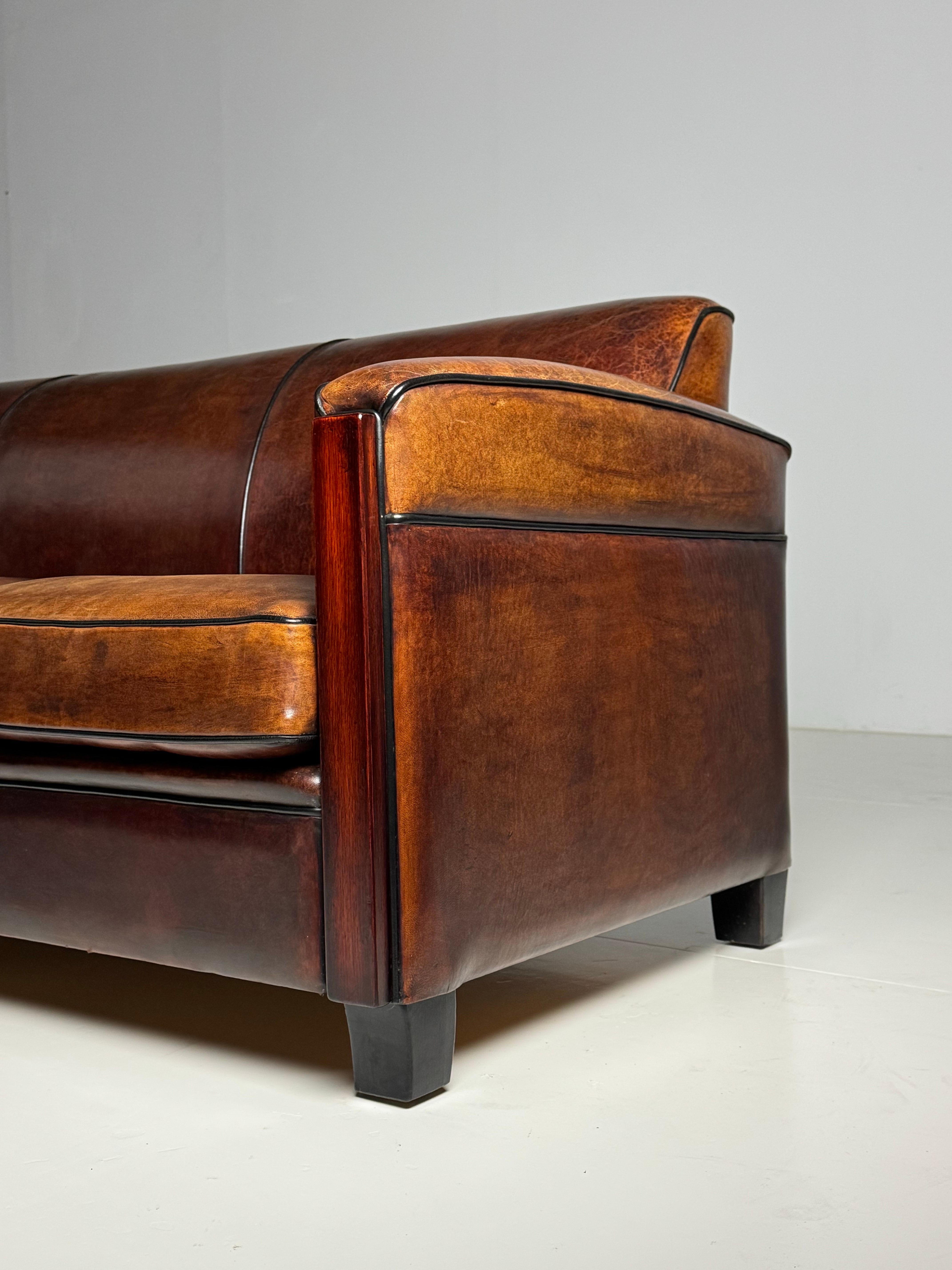 In neuwertigem Zustand!

3-Sitzer-Sofa im Art-Déco-Stil. Hergestellt von Lounge Atelier im Jahr 1992.

Mit hochwertigem Schafsleder gepolstert und mit schwarzen Paspeln versehen. Hat im Laufe der Jahre eine schöne Patina angenommen. Sehr bequem zu