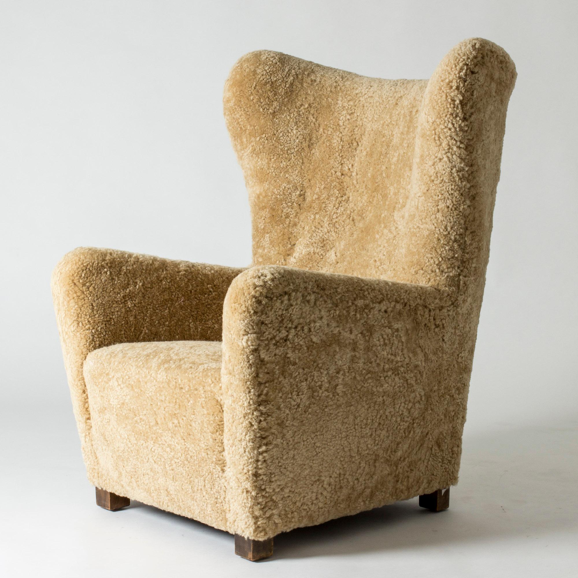 Elegant 1930s lounge chair from Fritz Hansen, with clean, stately lines. Upholstered with sheepskin that softens the silhouette.