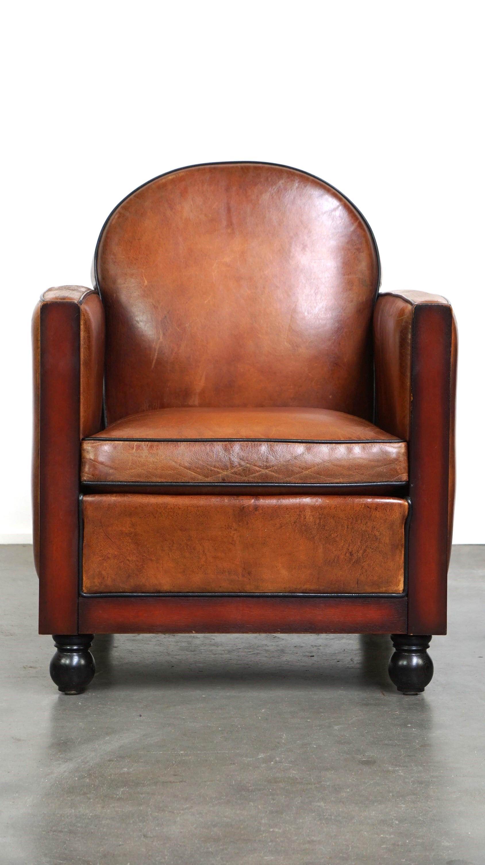 Offered: this sheepskin Art Deco design armchair finished with wood and stunning cognac-colored leather.

This wonderful Art Deco design armchair is made from sheepskin leather and features wooden details that give it its unique appearance. The