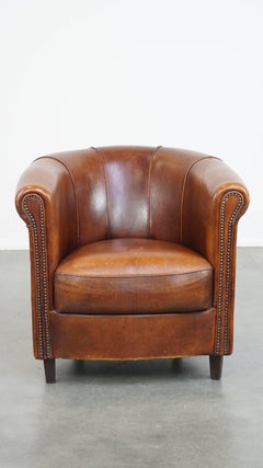 Sheepskin club armchair in a charming cognac color with piping on the backrest