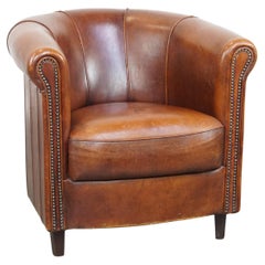 Fauteuil club en peau de mouton d'une charmante couleur cognac avec passepoil sur le dossier