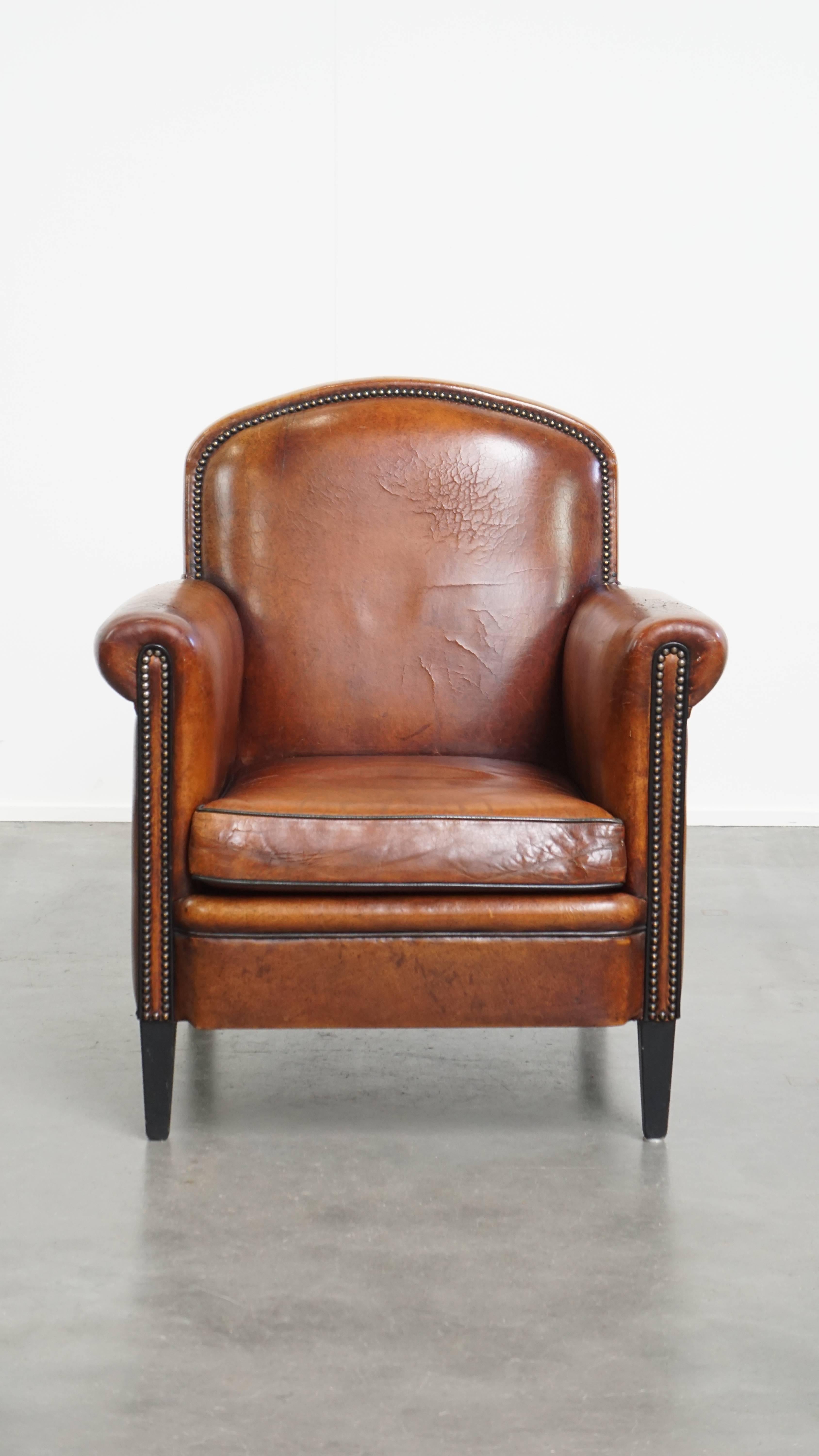 Offered: this stylish sheepskin leather design armchair in a warm cognac color, finished with black piping and decorative studs.
This elegant and timeless sheepskin armchair can be easily integrated into almost any interior. Thanks to its warm color