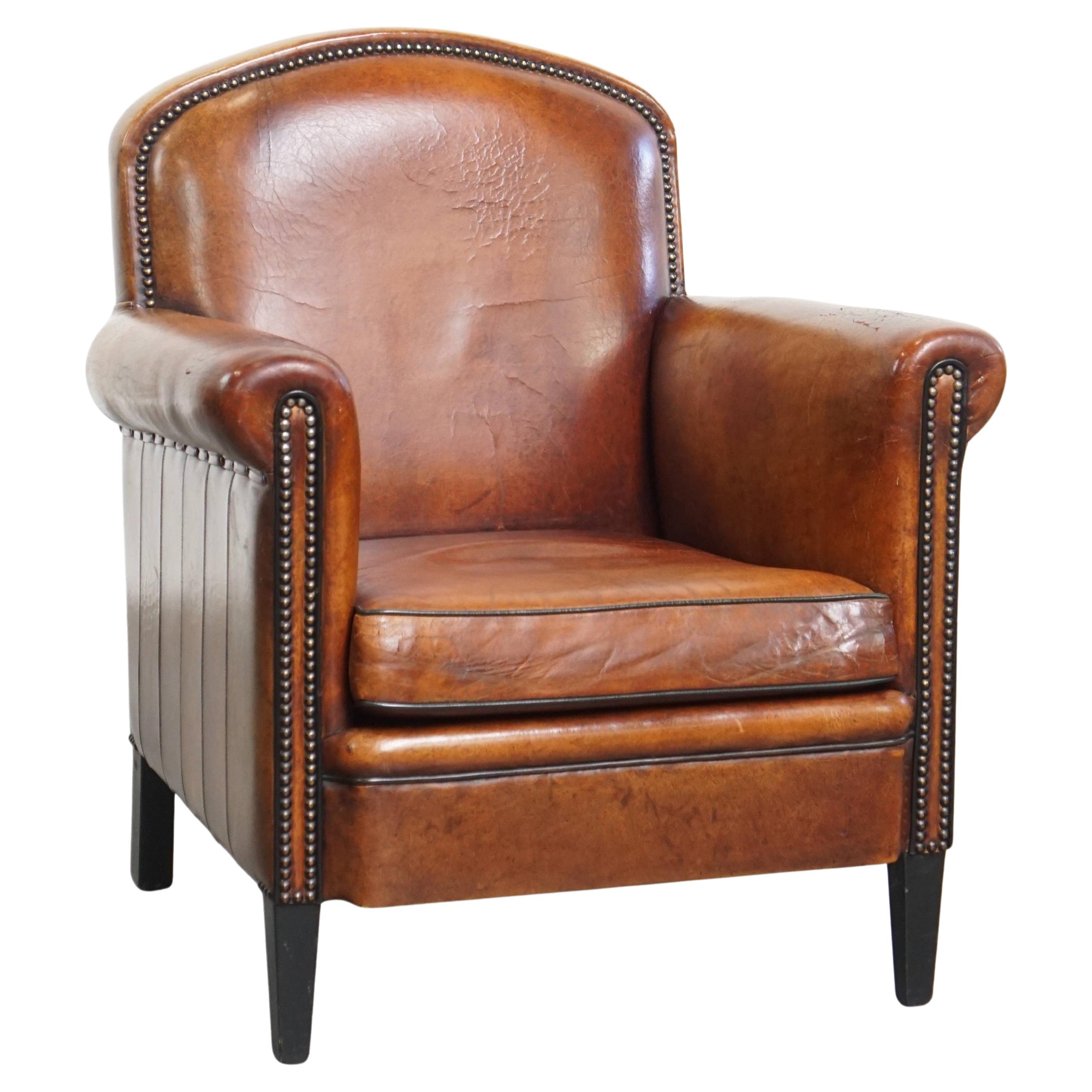 Poltrona in pelle di pecora color cognac con bordature nere