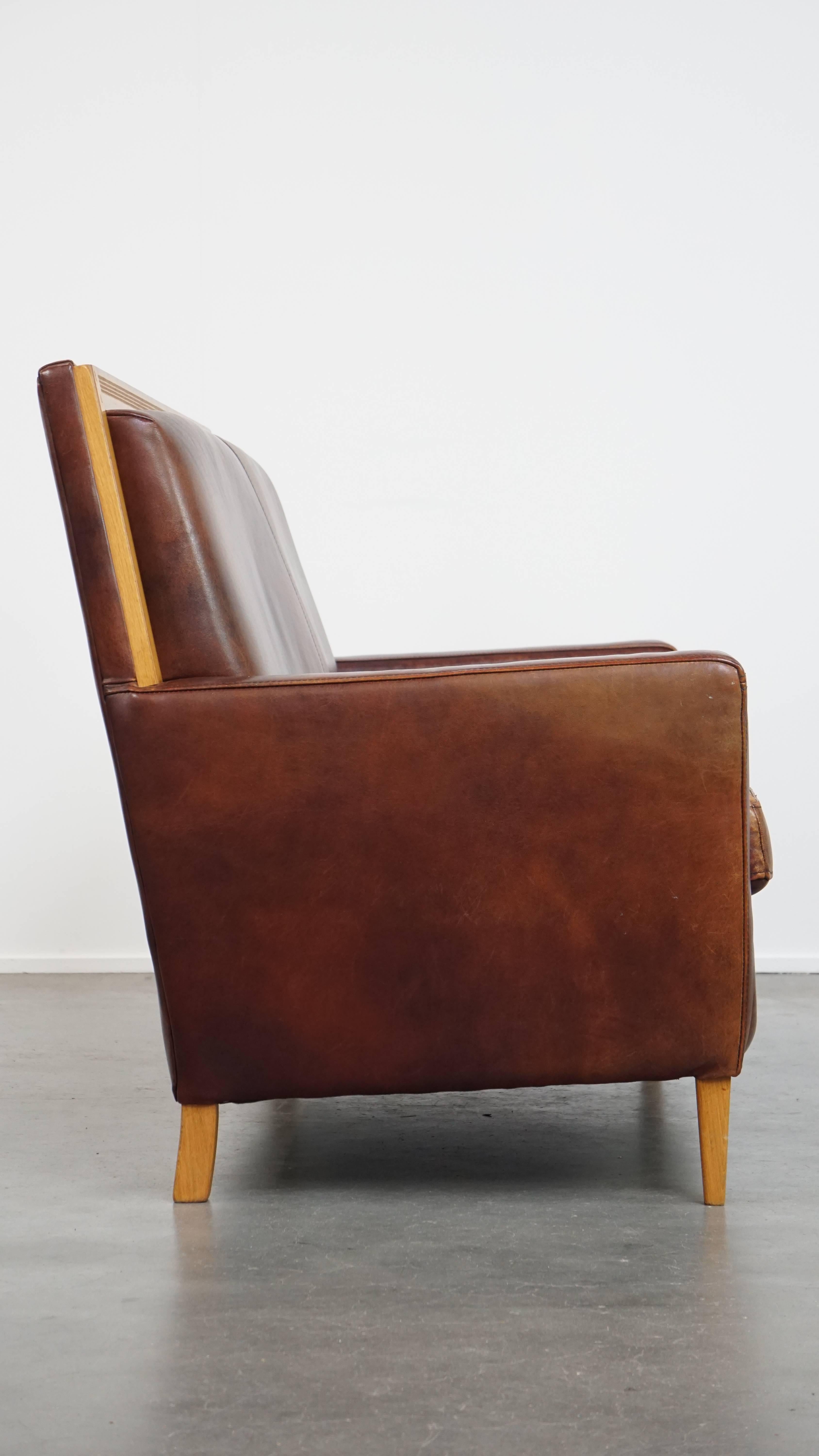 Angeboten wird hier dieses schöne und bequeme Schafsleder Art Deco Design 2-Sitzer Sofa mit Holzdetails.

Dieses elegante Art-Déco-Sofa fügt sich nahtlos in klassische und moderne Interieurs ein. Dank seiner warmen Cognac-Töne verleiht er jedem Raum