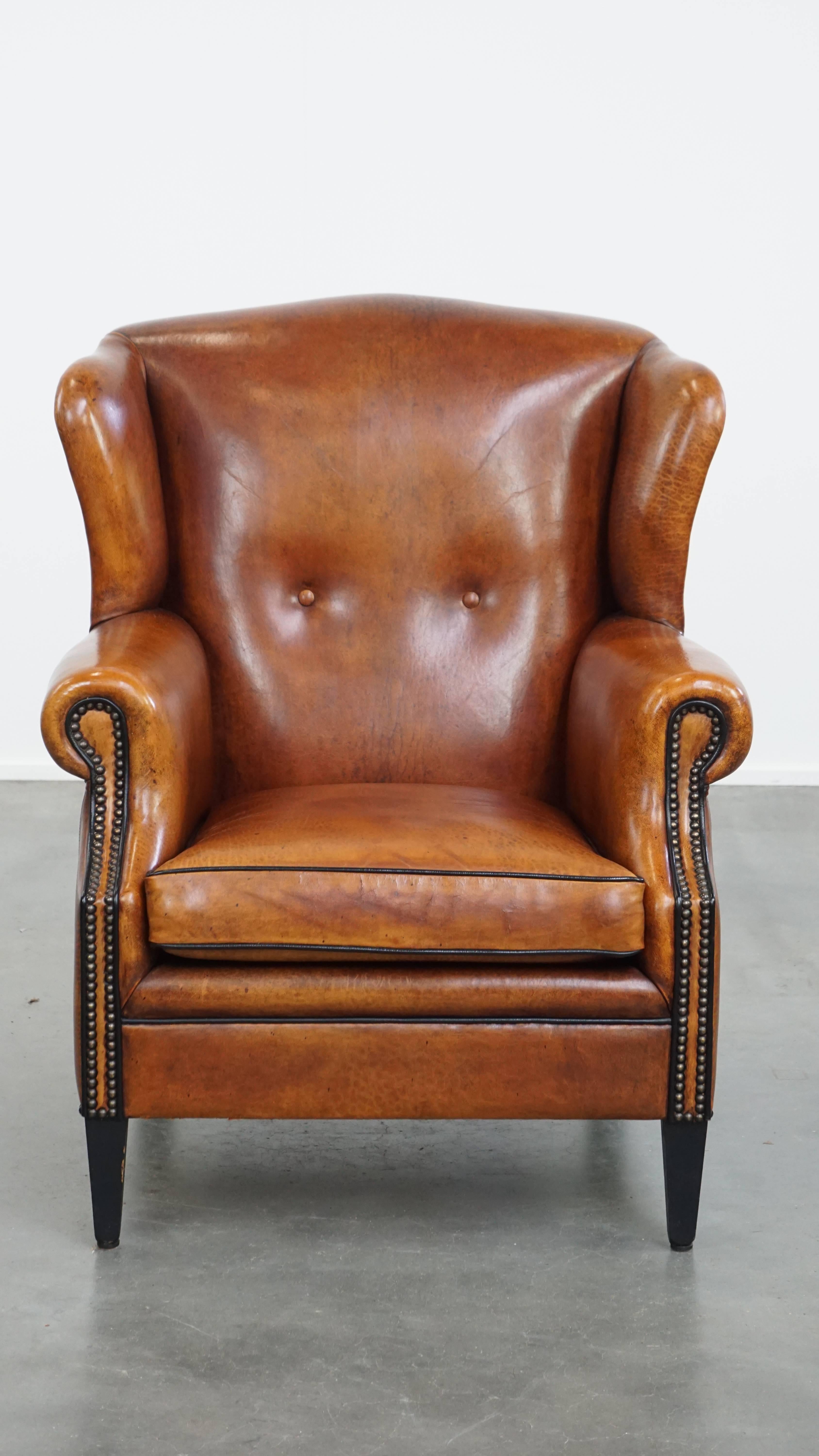 Offered: this comfortable sheepskin leather wingback armchair with a beautiful warm colour palette and refined stitching on the sides. This luxurious wingback chair, crafted from sheepskin leather, fits perfectly in both classic and modern