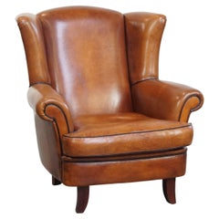 Fauteuil à oreilles en peau de mouton avec passepoil noir