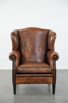 Sheepskin wingback armchair with decorative nails and black piping