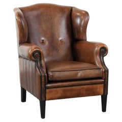 Sheepskin wingback armchair with decorative nails and black piping