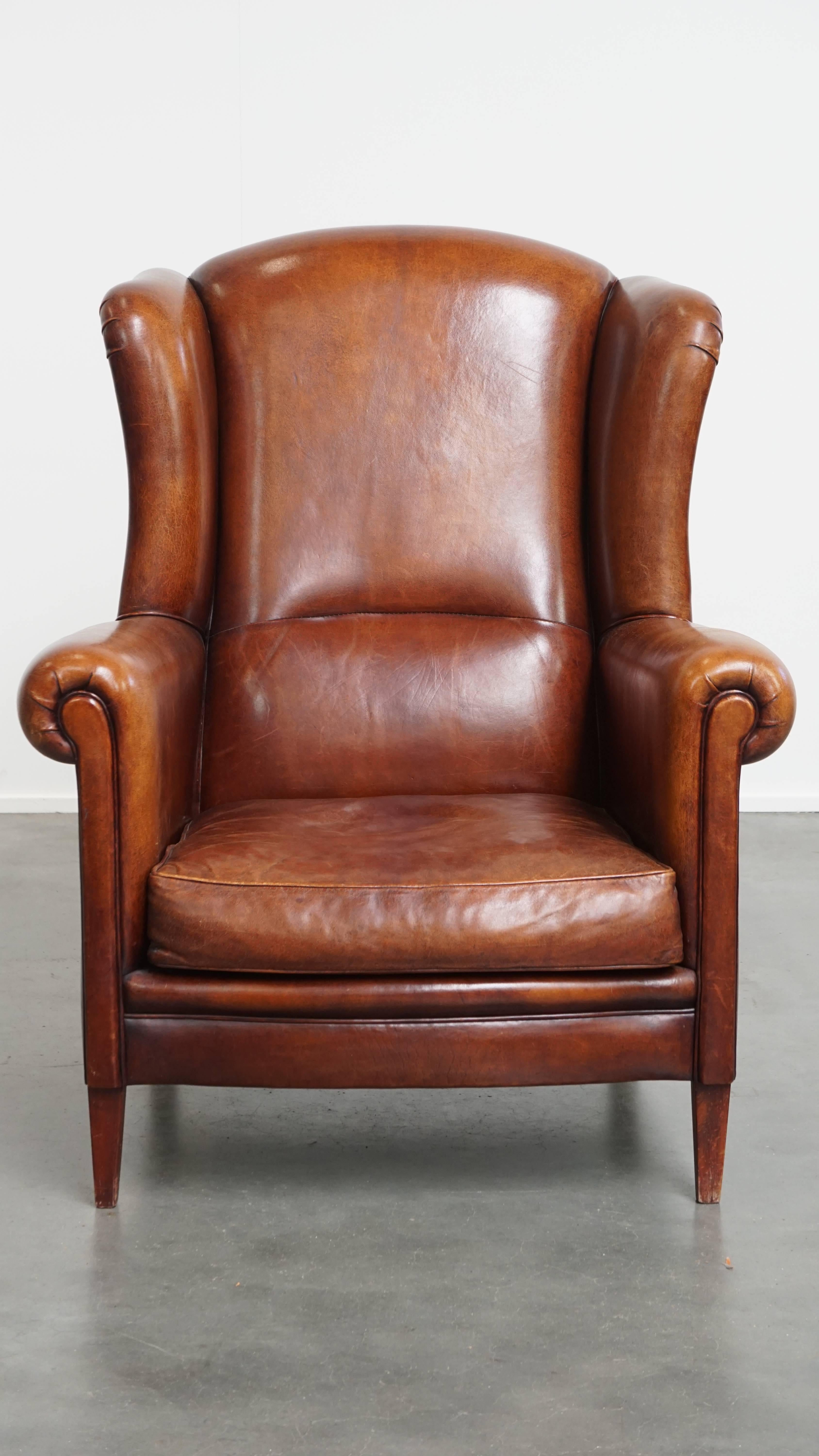 Offered here is this large, characterful, and timeless sheepskin wingback armchair with a luxurious finish. 

This beautiful armchair, featuring warm tones, is made of genuine sheepskin leather. The matching piping and elegant design give the chair