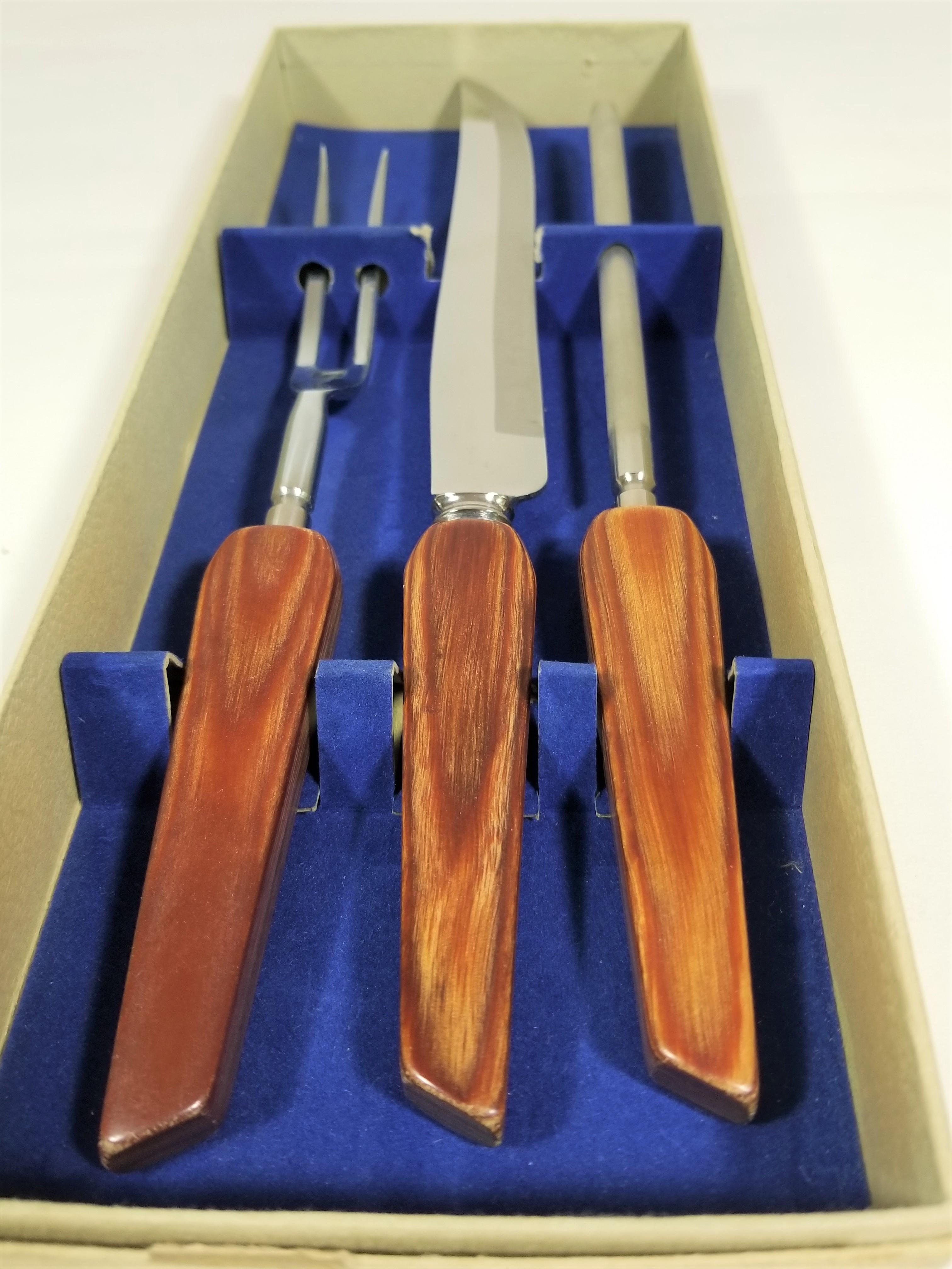 Nie benutzt und noch im Originalkarton. Besteckset aus der Mitte des Jahrhunderts, hergestellt in England von Sheffield. Griffe aus Palisanderholz. Rostfreie Utensilien. Gabel, Tranchiermesser und Messerschärfer. Ausgezeichneter